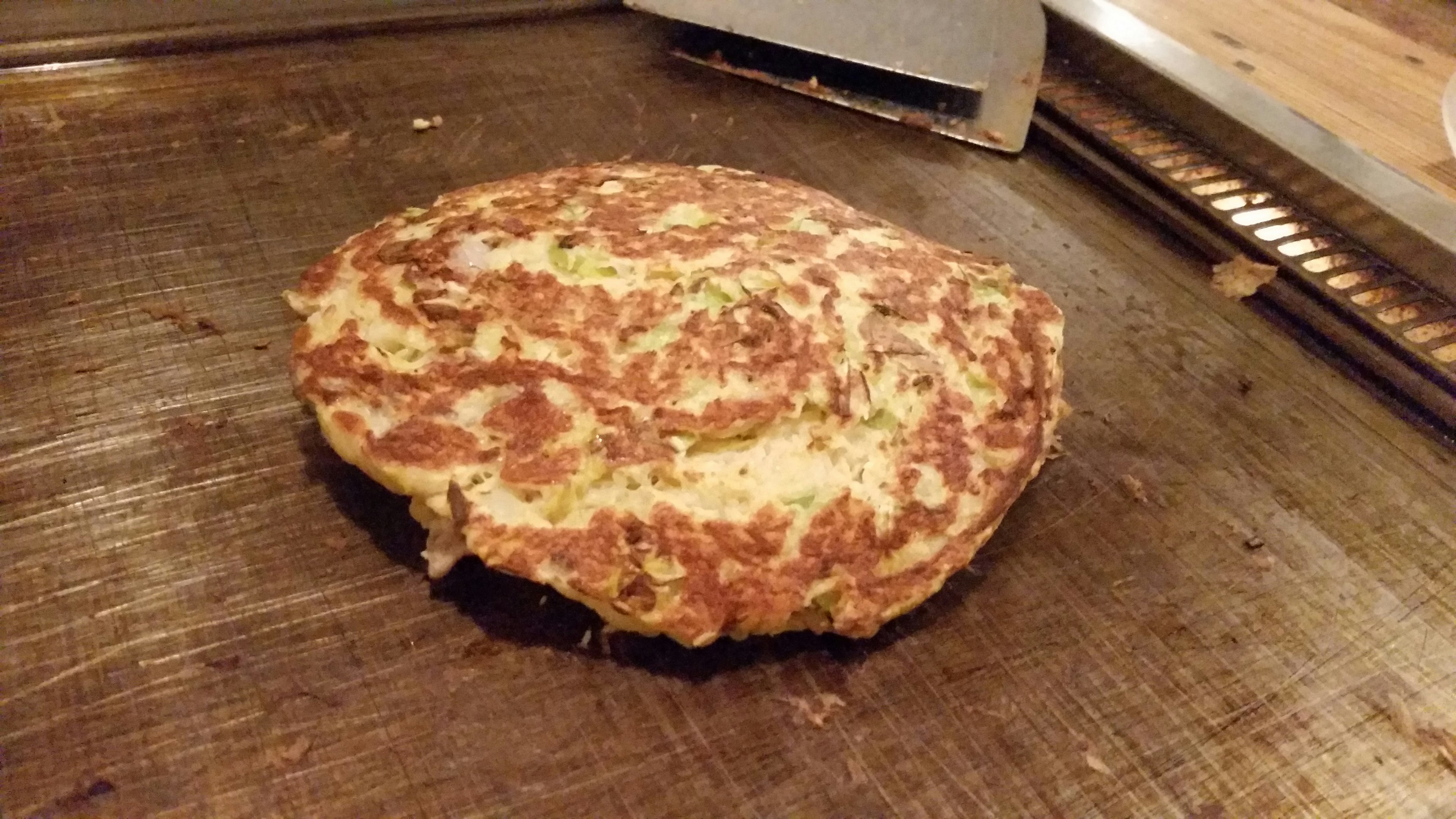 Okonomiyaki yang dimasak di atas panggangan panas