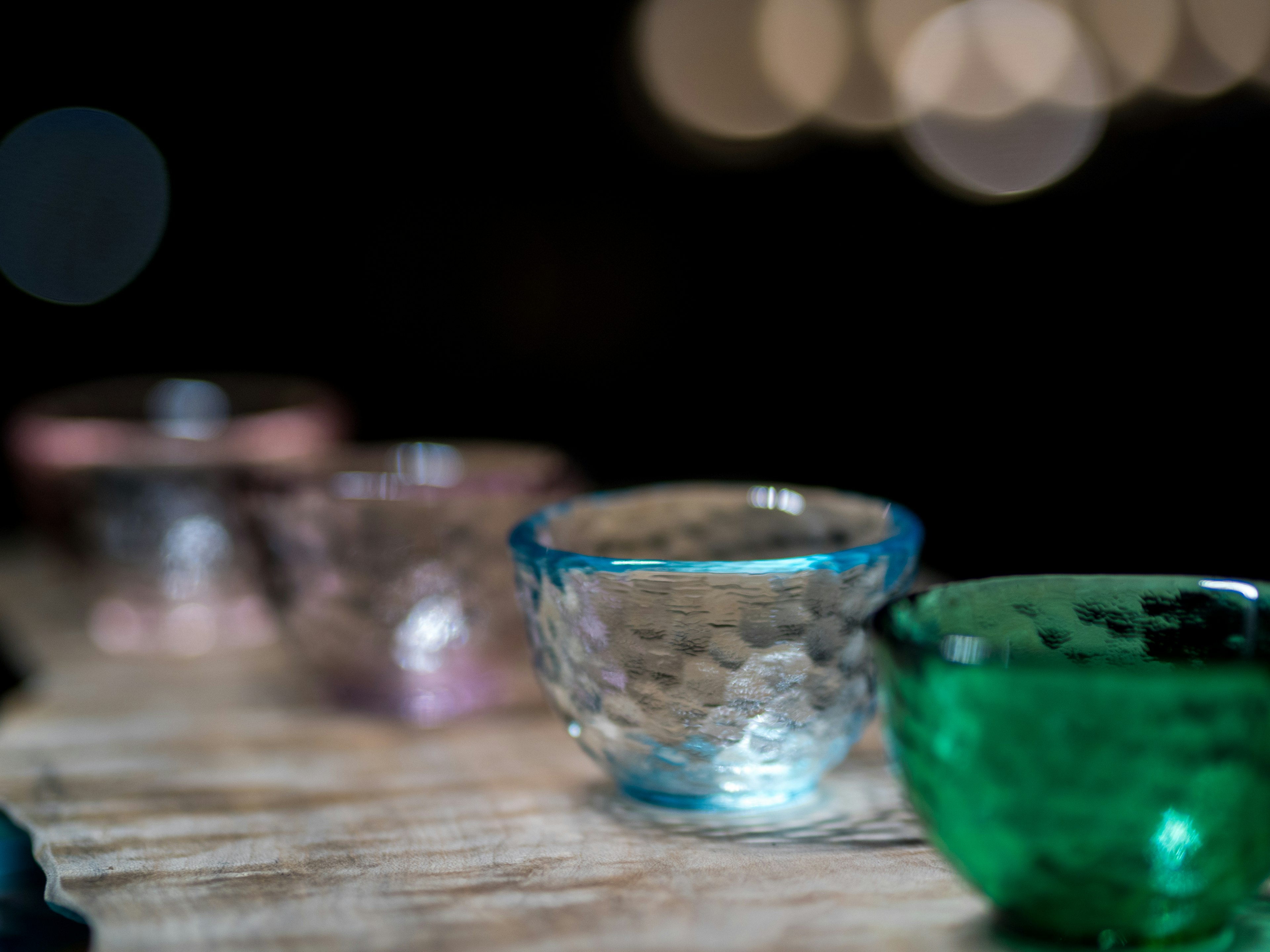 Colorful small glass bowls arranged on a wooden surface