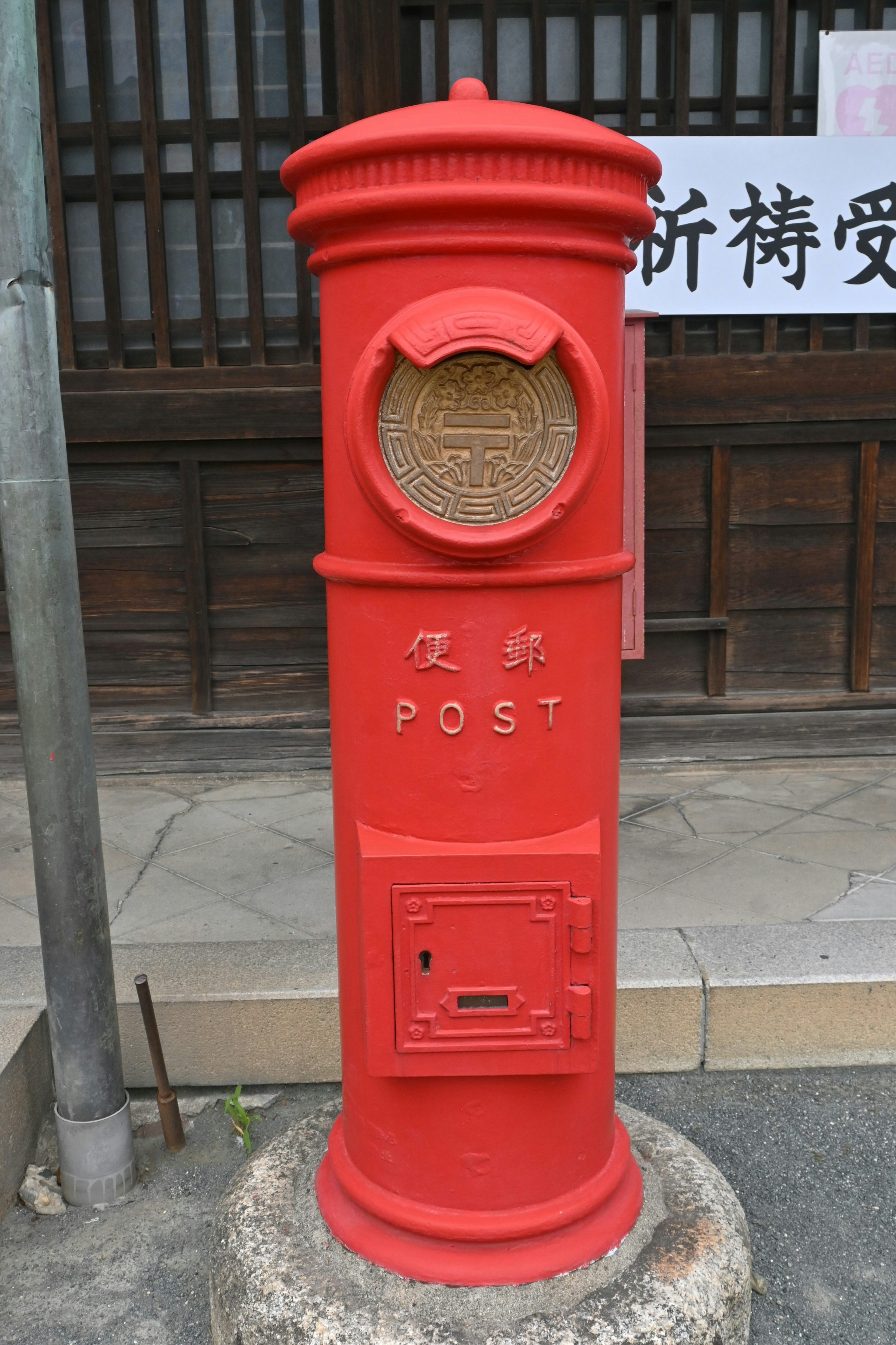 A red postal box standing in a street setting