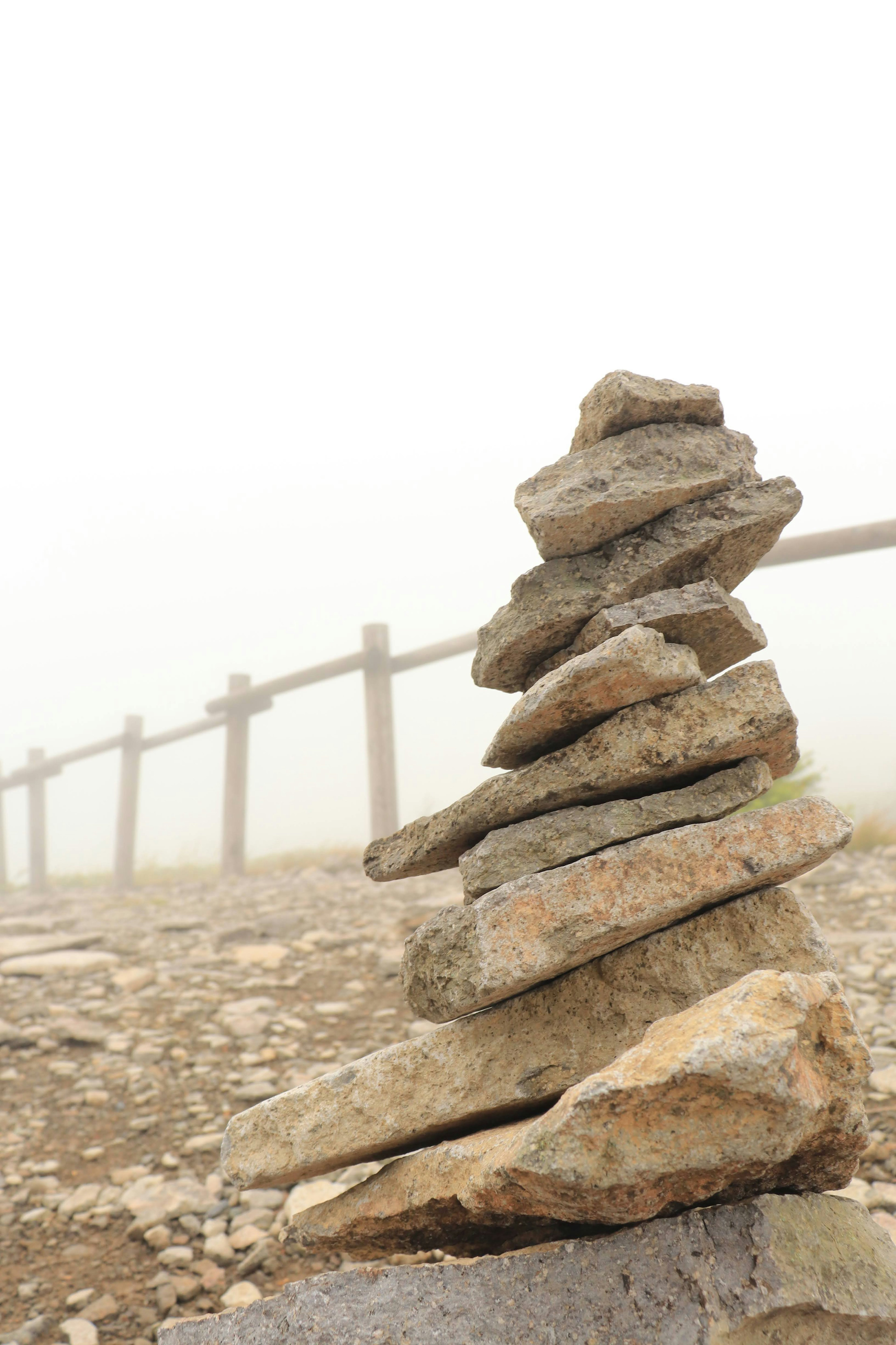 Pila de piedras en la niebla con cerca de madera