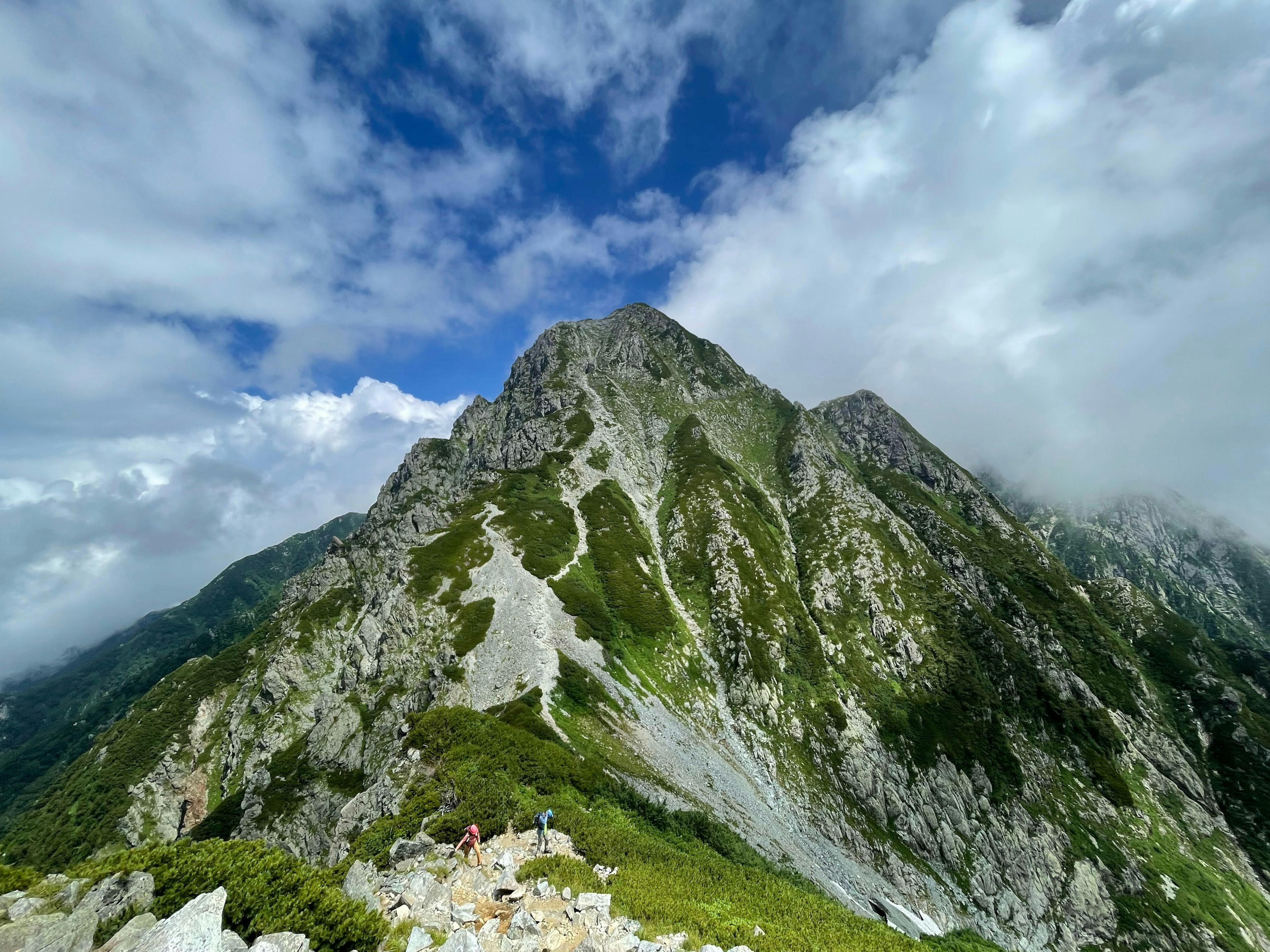 Vista maestosa di una montagna coperta di nuvole pendii verdi e terreno roccioso