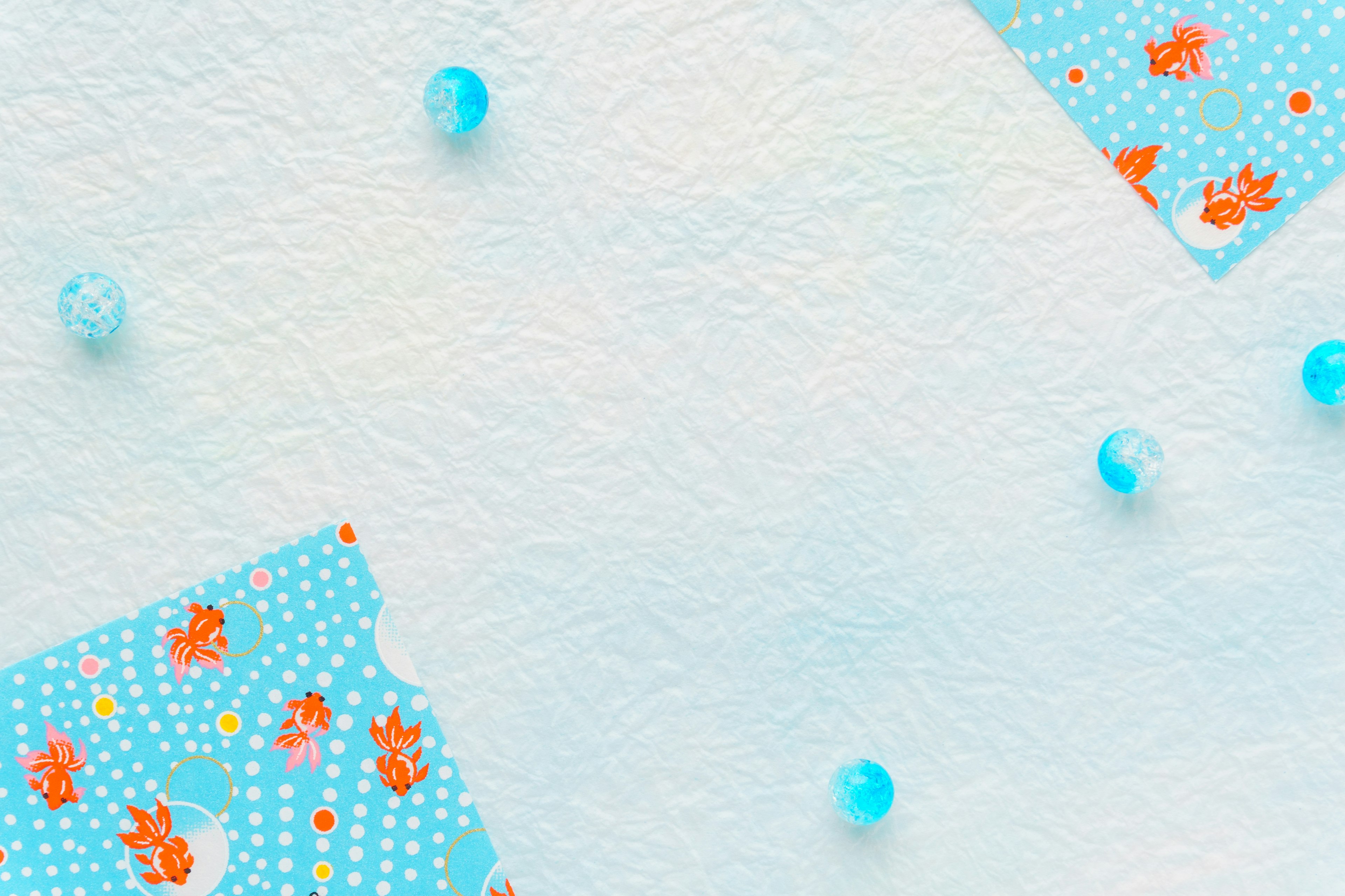 Blue background with floral patterned paper pieces and transparent beads scattered