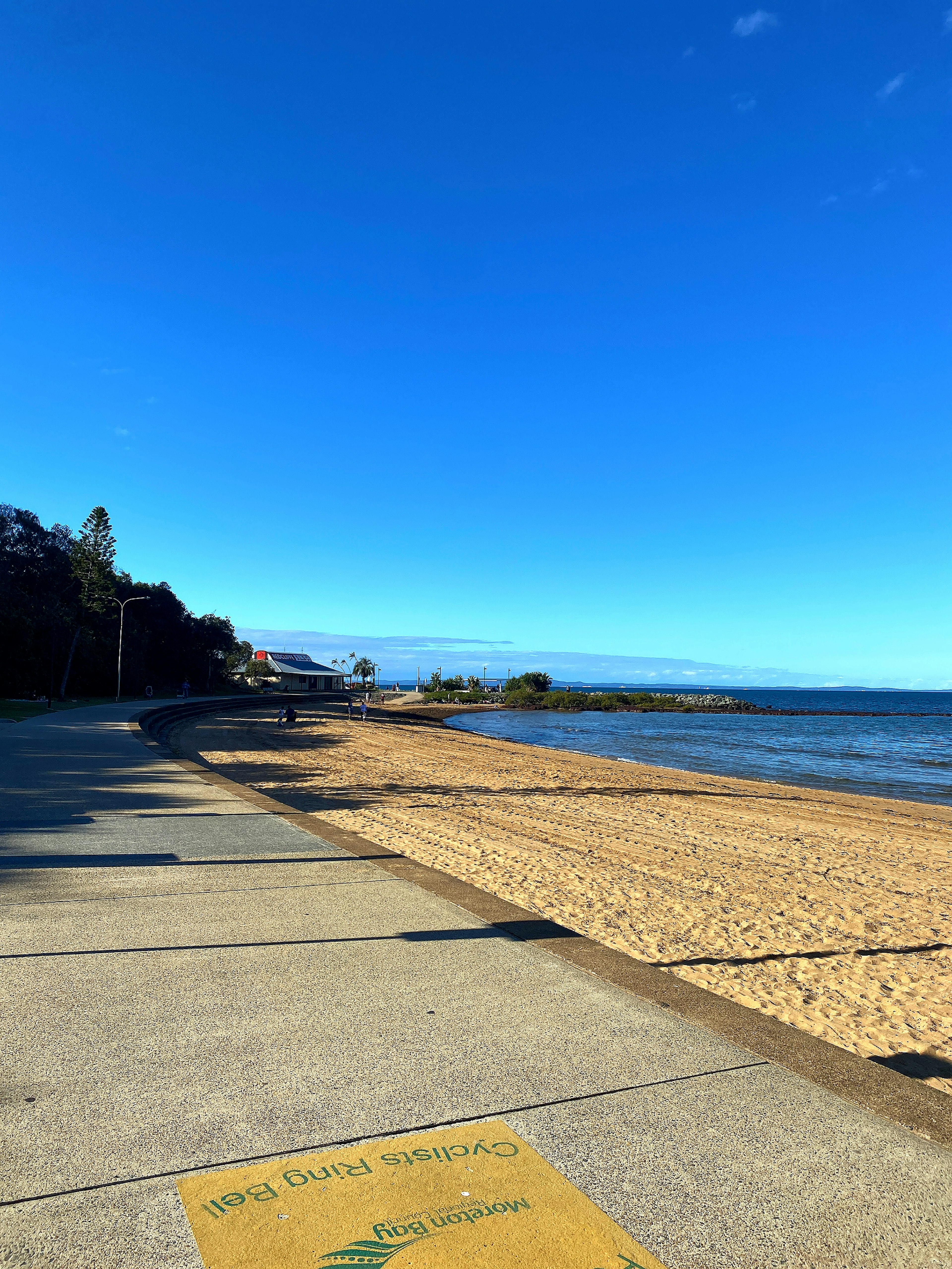 Coastal walkway beside sandy beach and clear blue sky