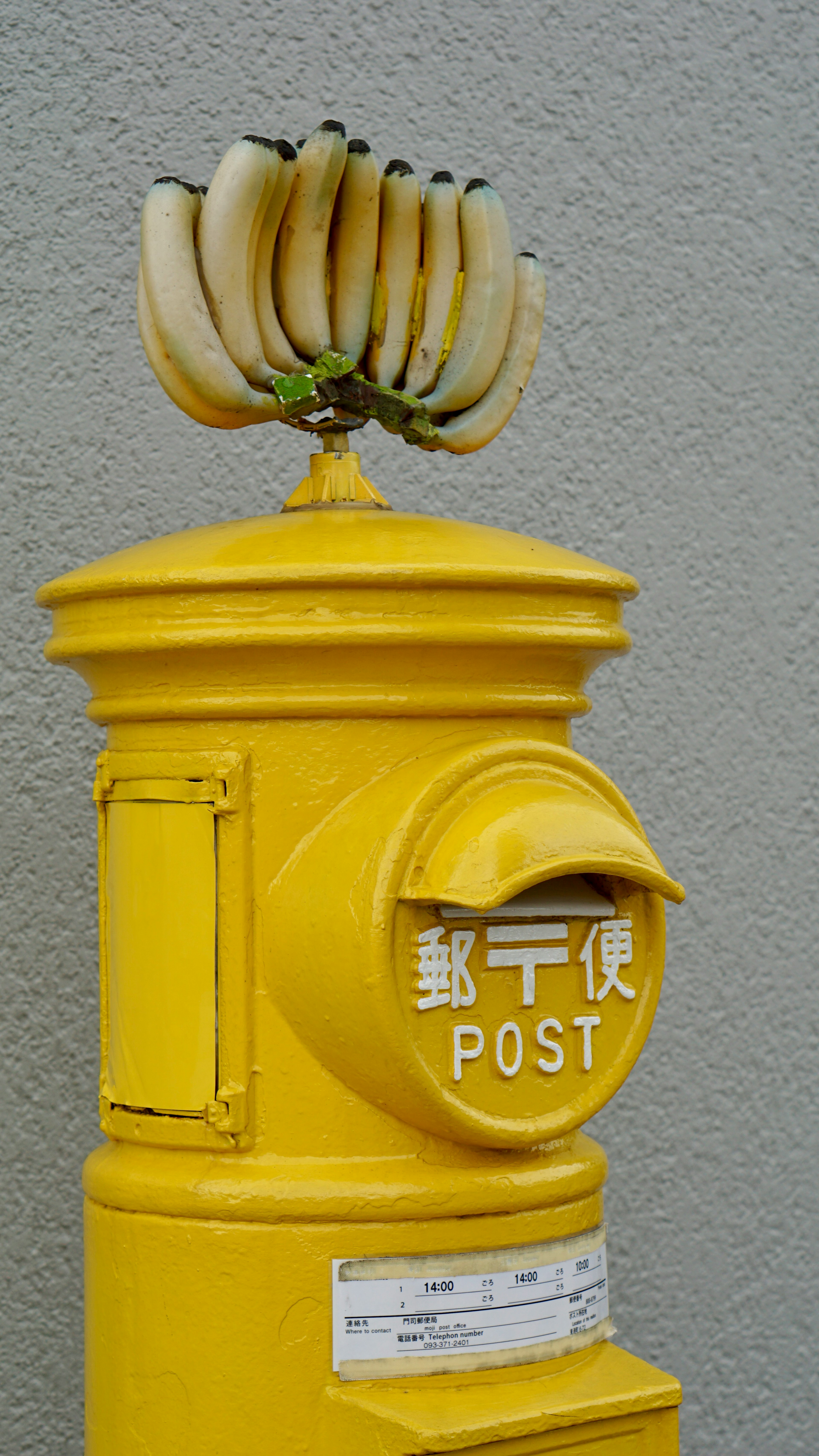 A unique scene with bananas atop a yellow postal box