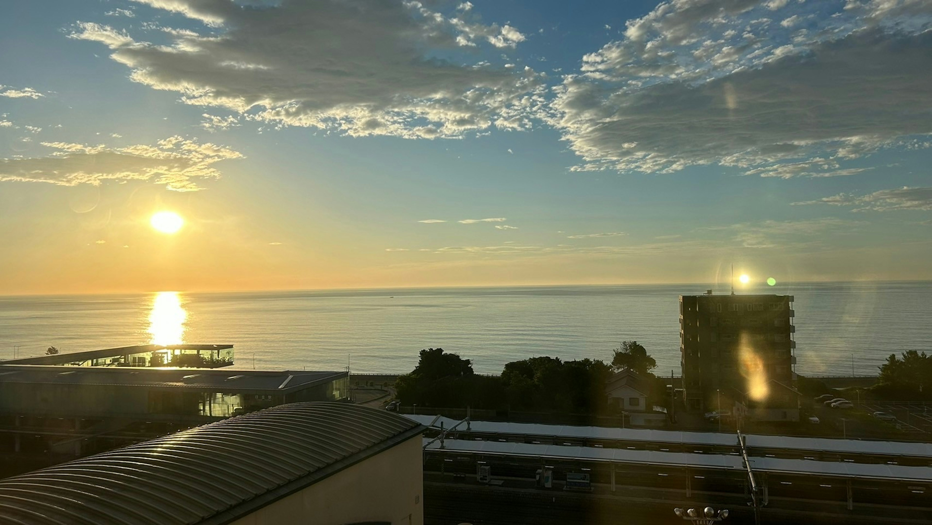 海に沈む夕日とビルのシルエットが映える風景