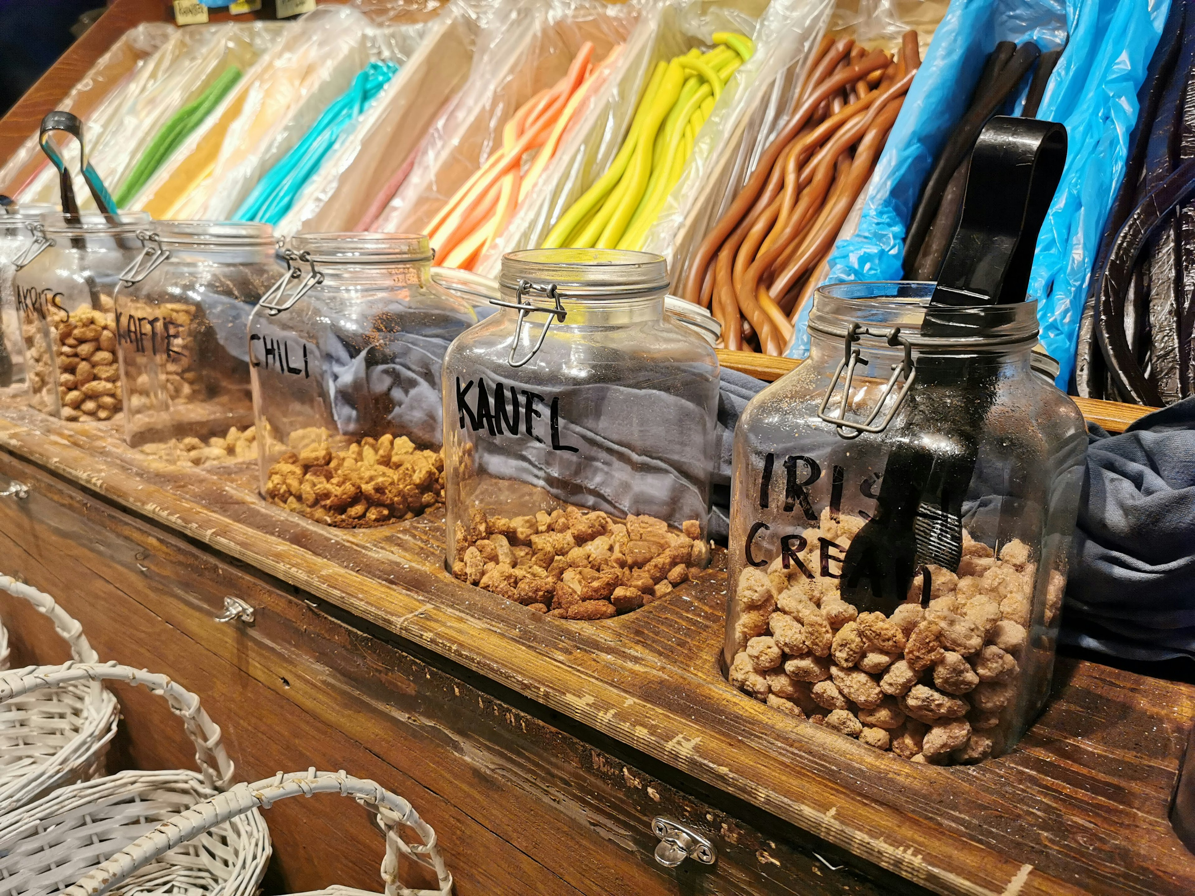 Frascos de vidrio llenos de dulces exhibidos en una tienda con caramelos coloridos al fondo