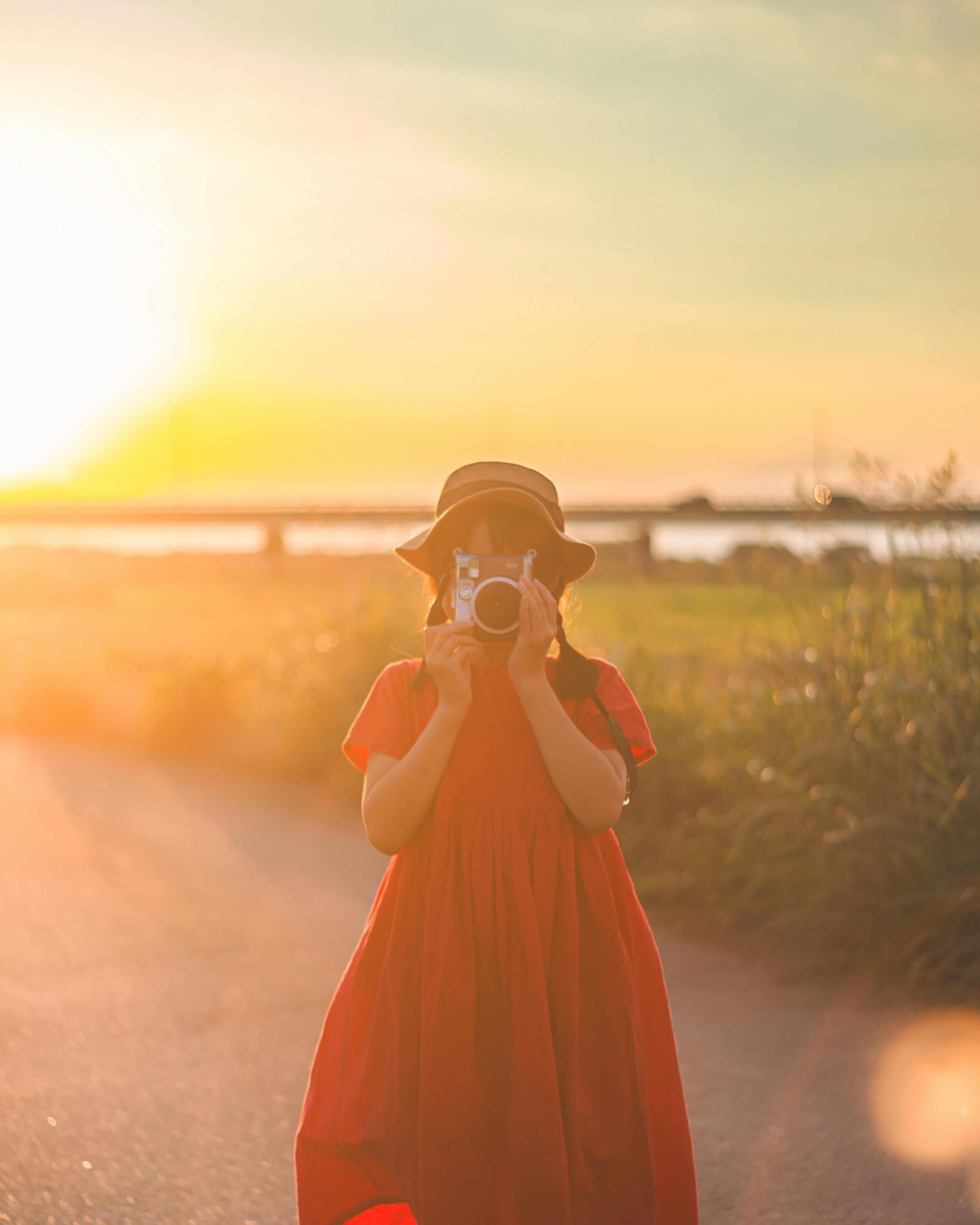 赤いドレスを着た女性がカメラを持っている夕日の風景