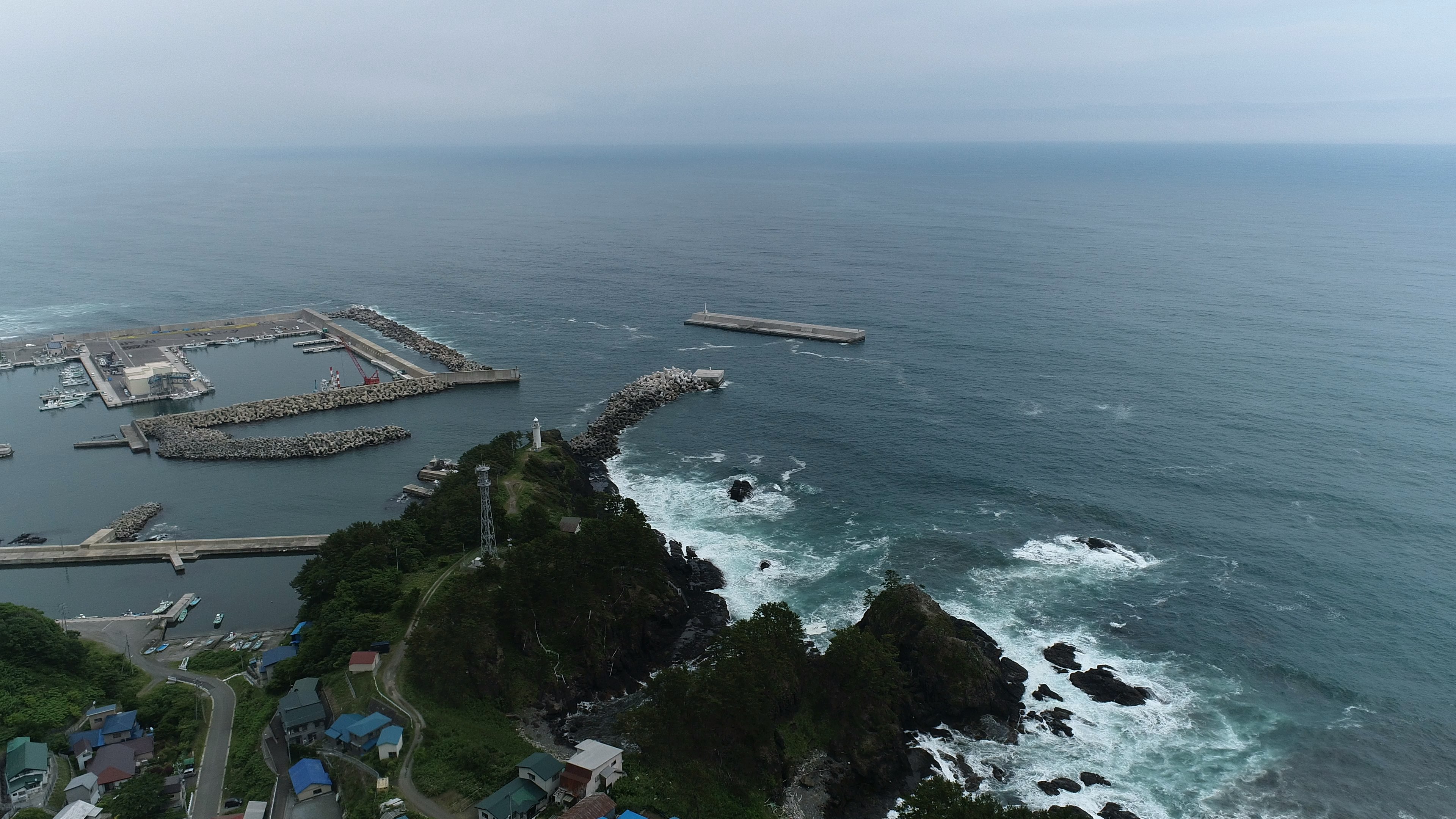 Pemandangan udara garis pantai dan pelabuhan Ombak menghantam batu Keberadaan mercusuar