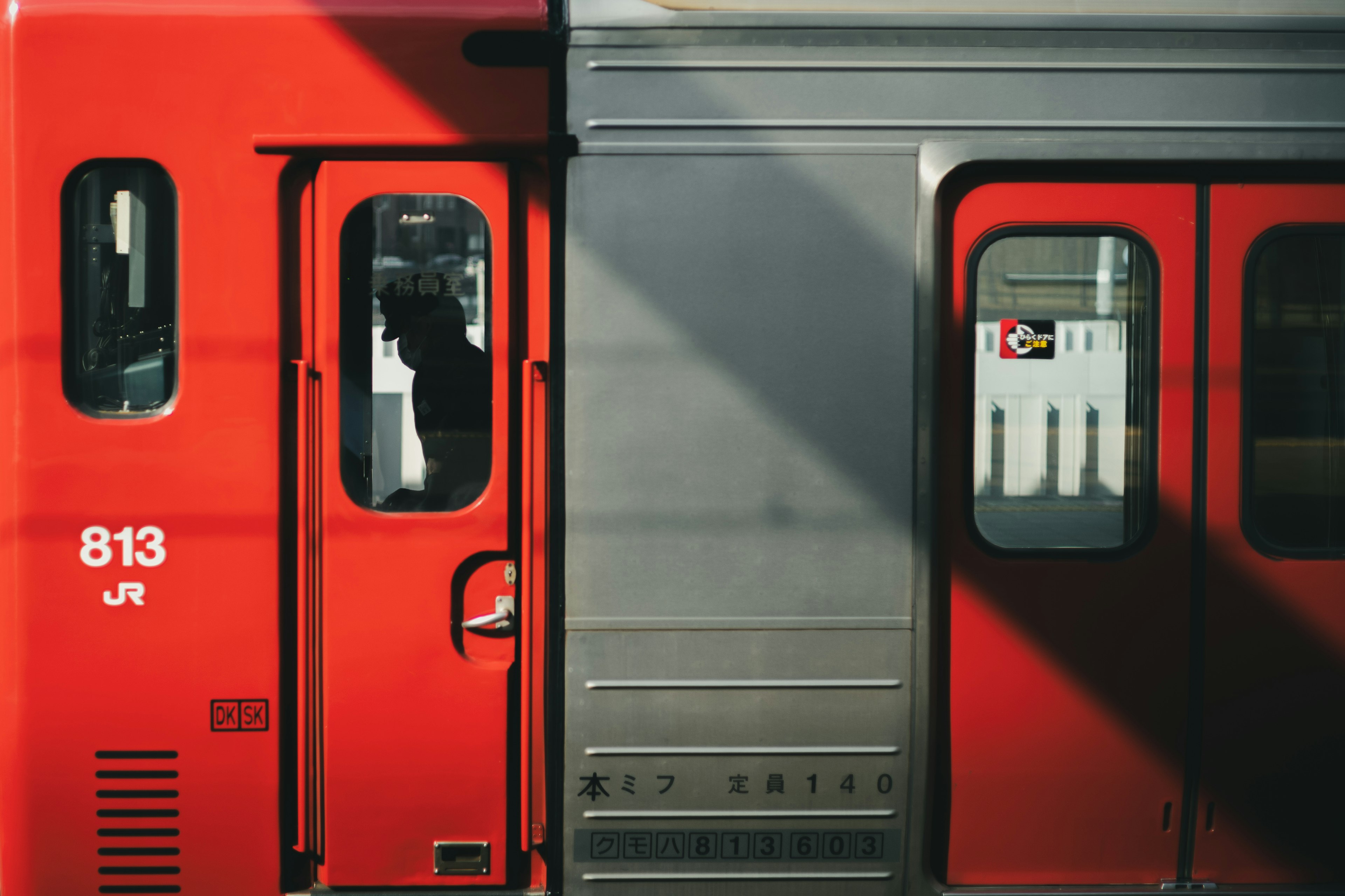 Close-up of a red train door and metallic side of the carriage