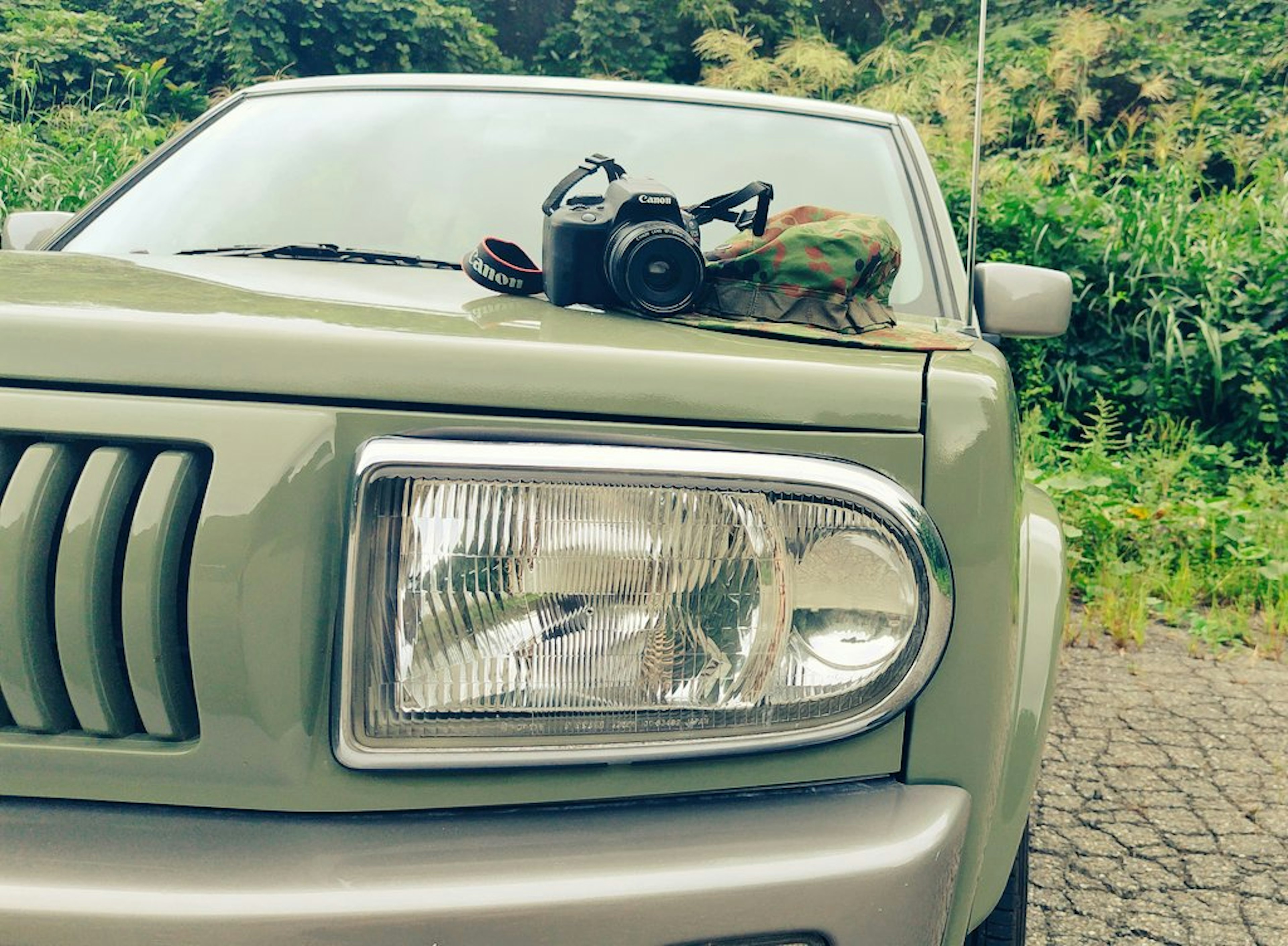 Un cofano di auto verde con una macchina fotografica e accessori sopra