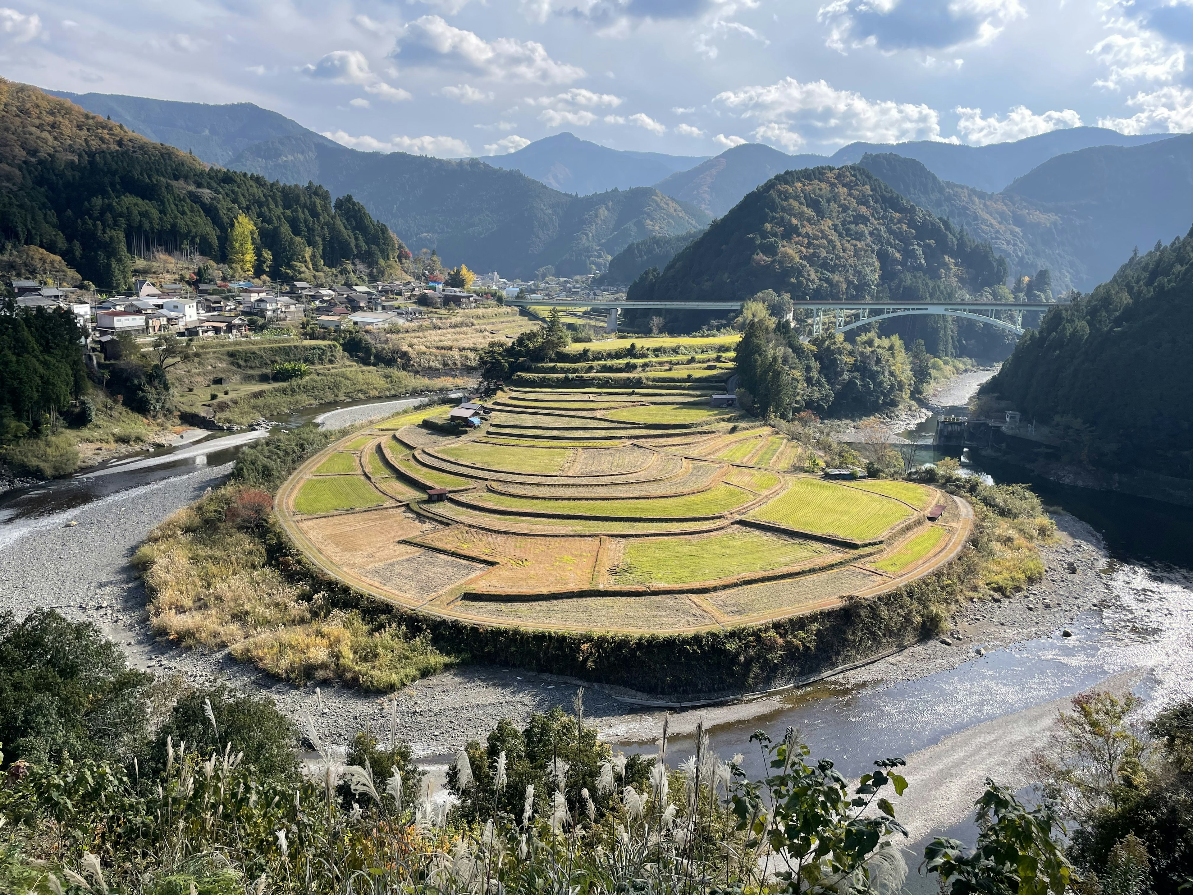 Panorama di risaie a terrazze in un paesaggio montano con un fiume che scorre