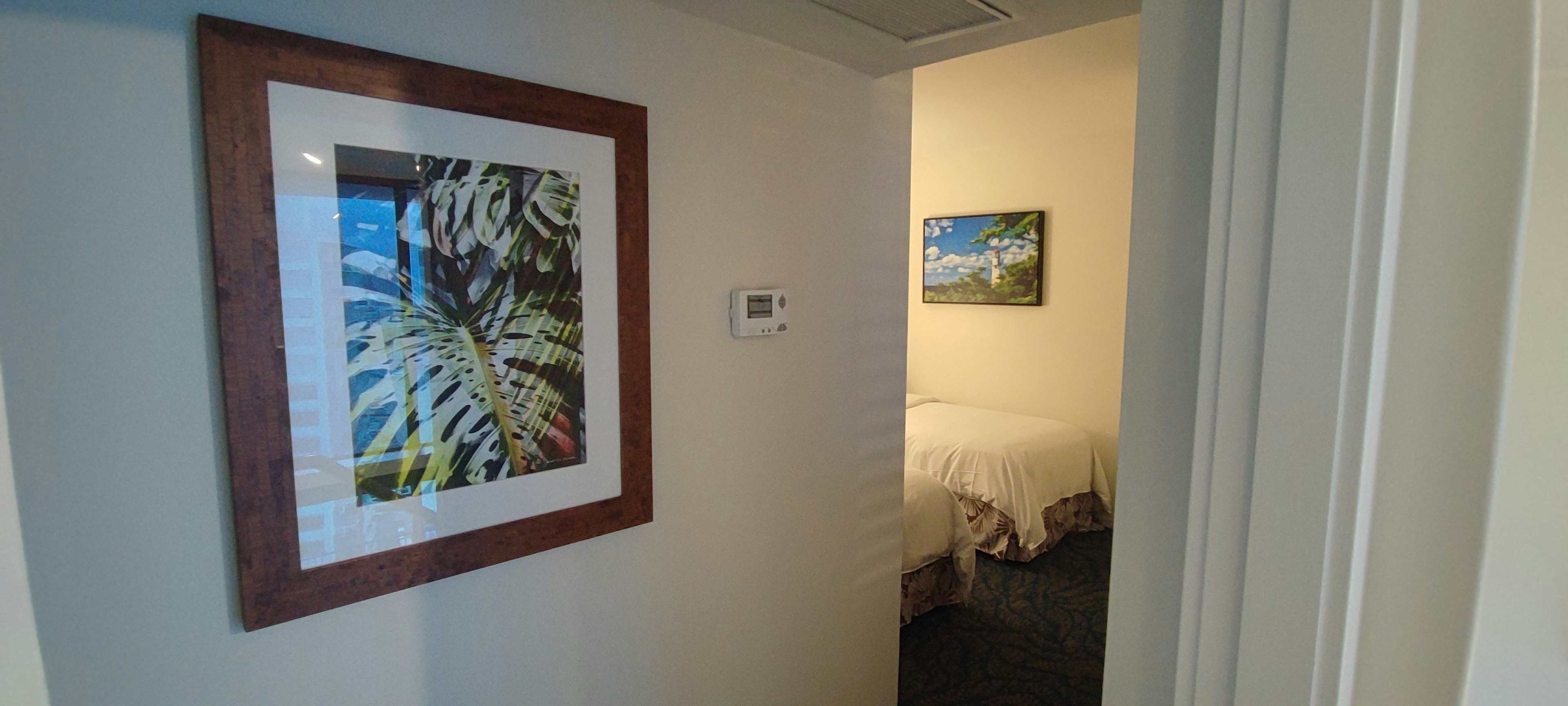 Art piece of green leaves at room entrance with bedroom in background