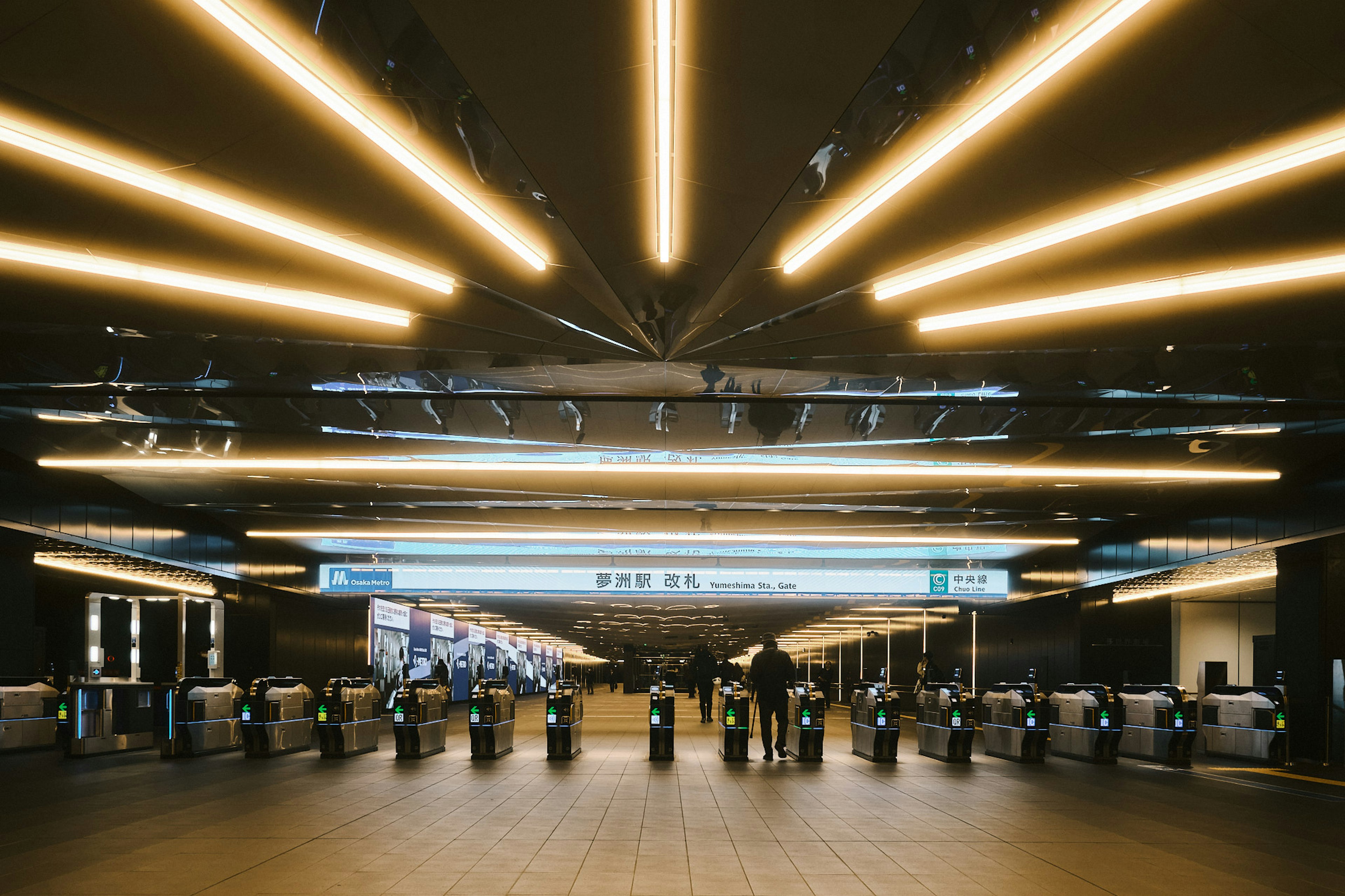 Intérieur moderne d'une gare avec un éclairage linéaire et des barrières à tickets des gens en mouvement