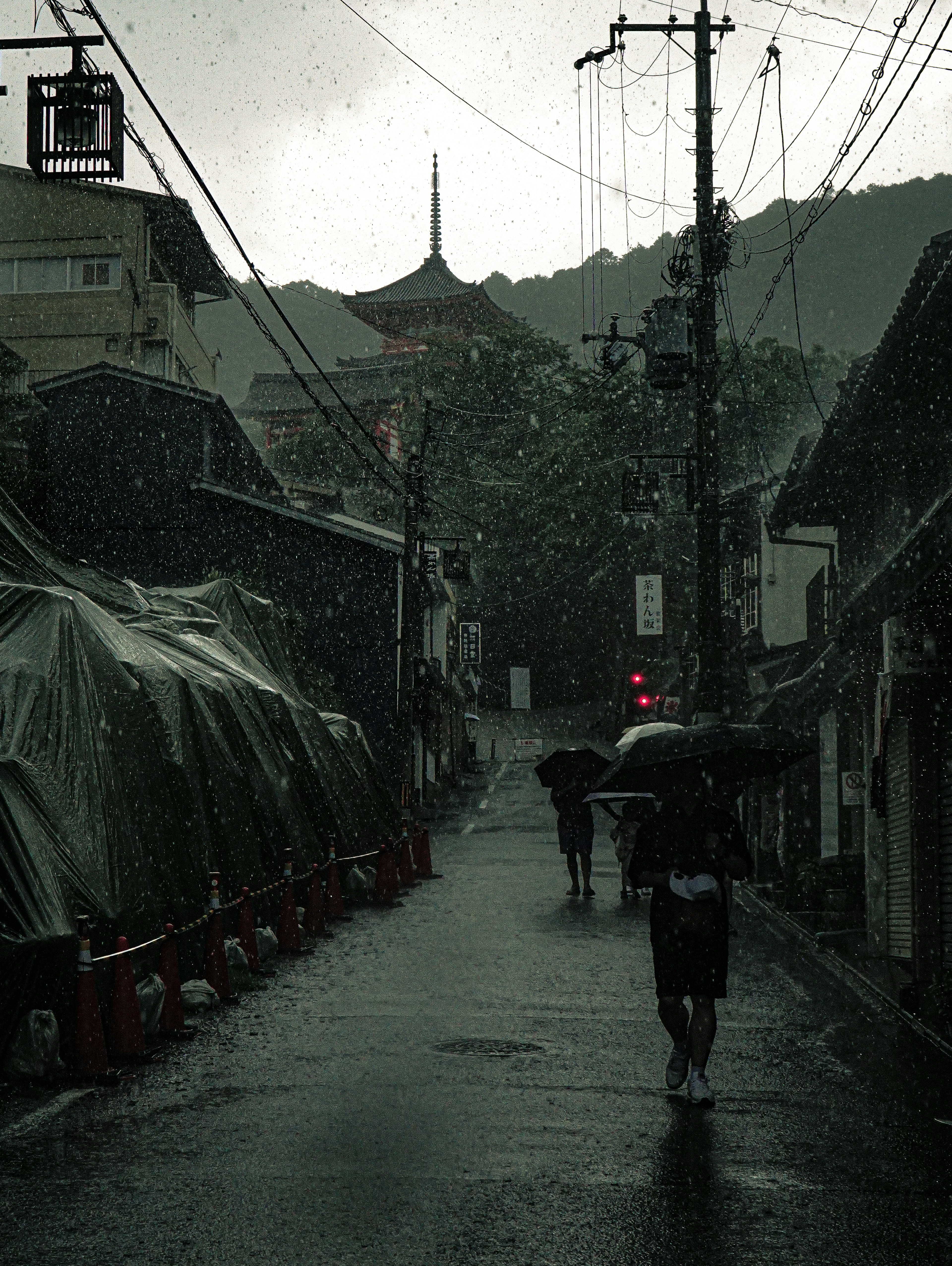 Des personnes marchant sous la pluie dans une rue tranquille avec une architecture traditionnelle