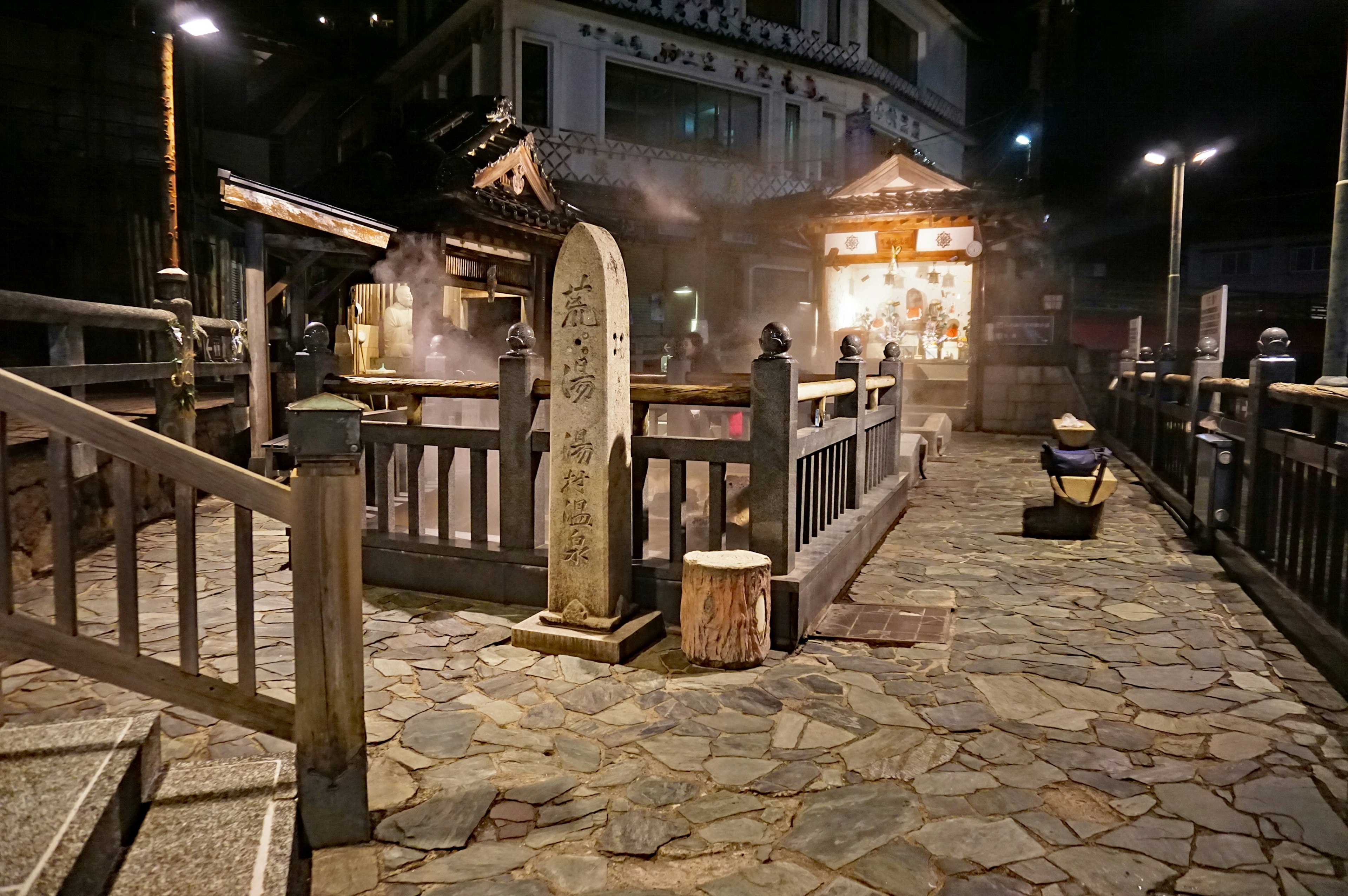 夜の温泉街の石畳と木製の橋が見える風景