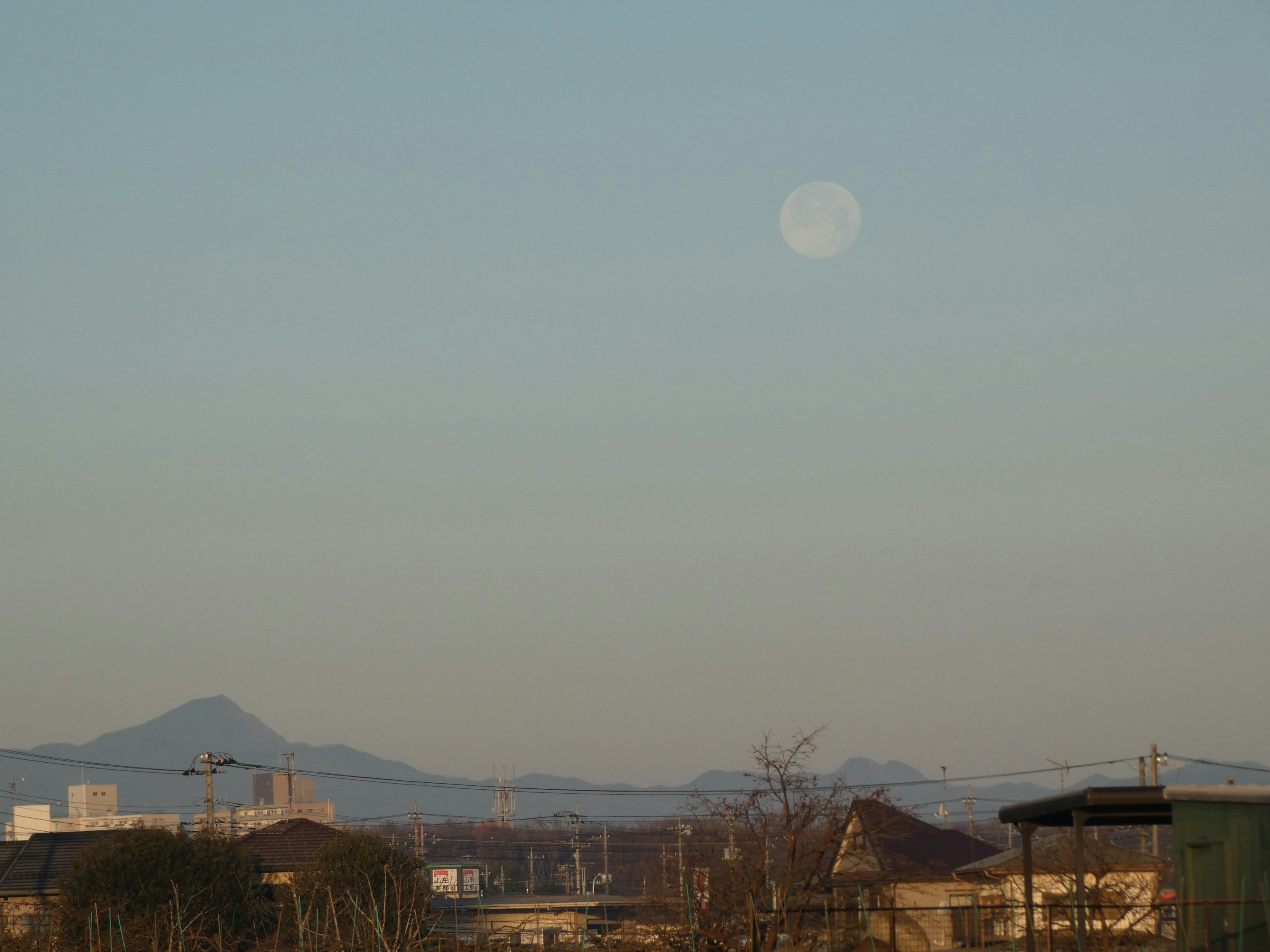 Paesaggio con la luna nel cielo blu e silhouette di montagne