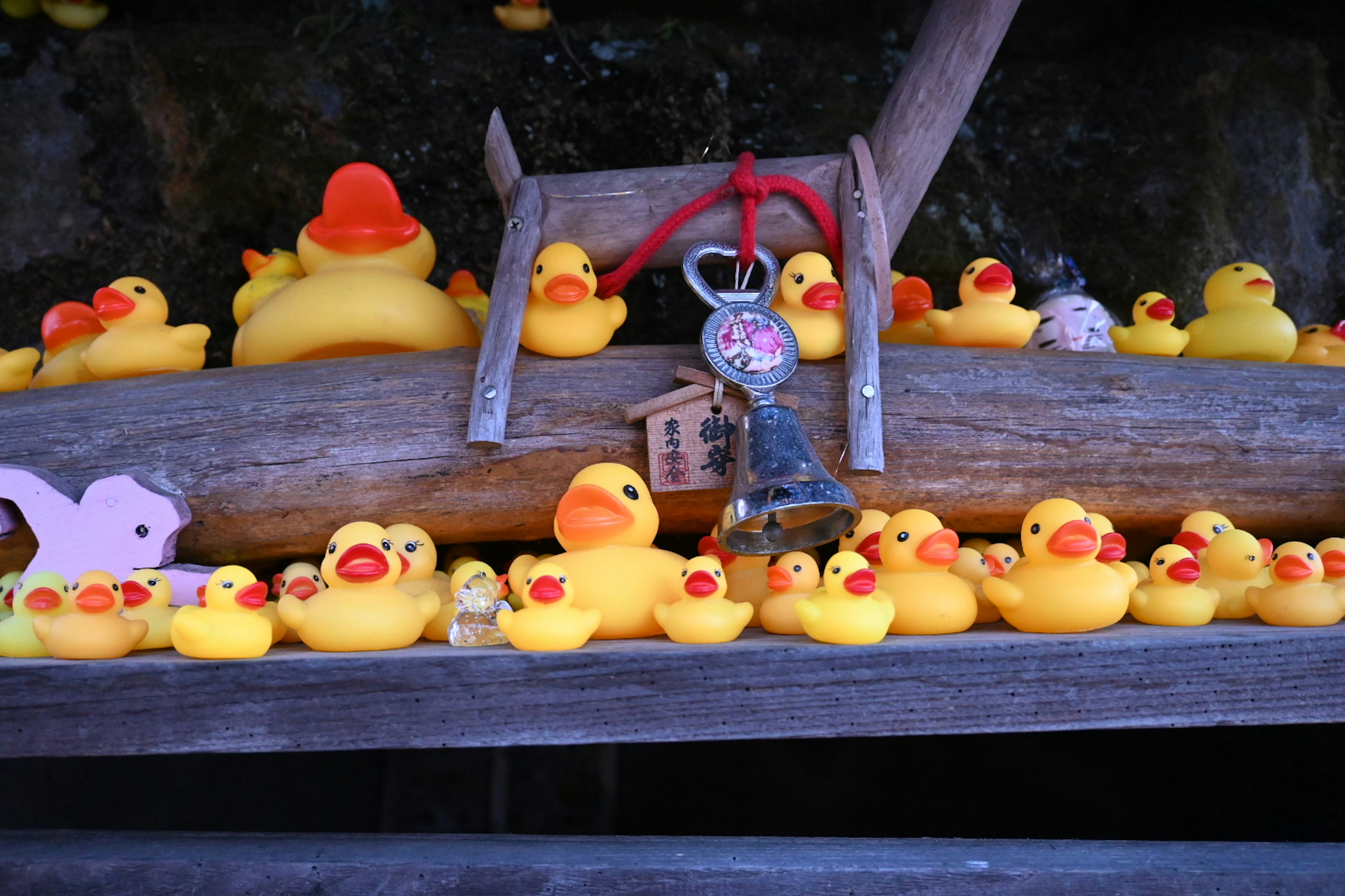 A shelf filled with yellow rubber ducks and a bell with a small decoration