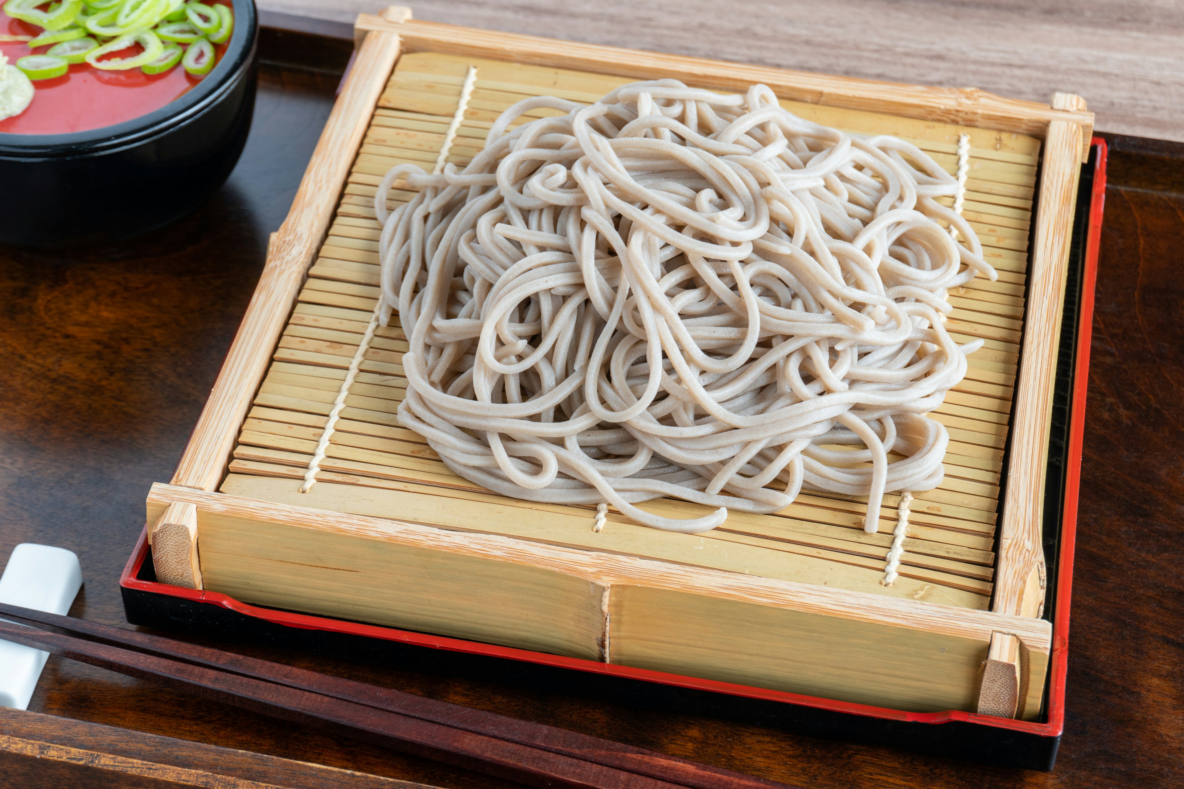 Un plato de fideos soba presentado sobre una estera de bambú