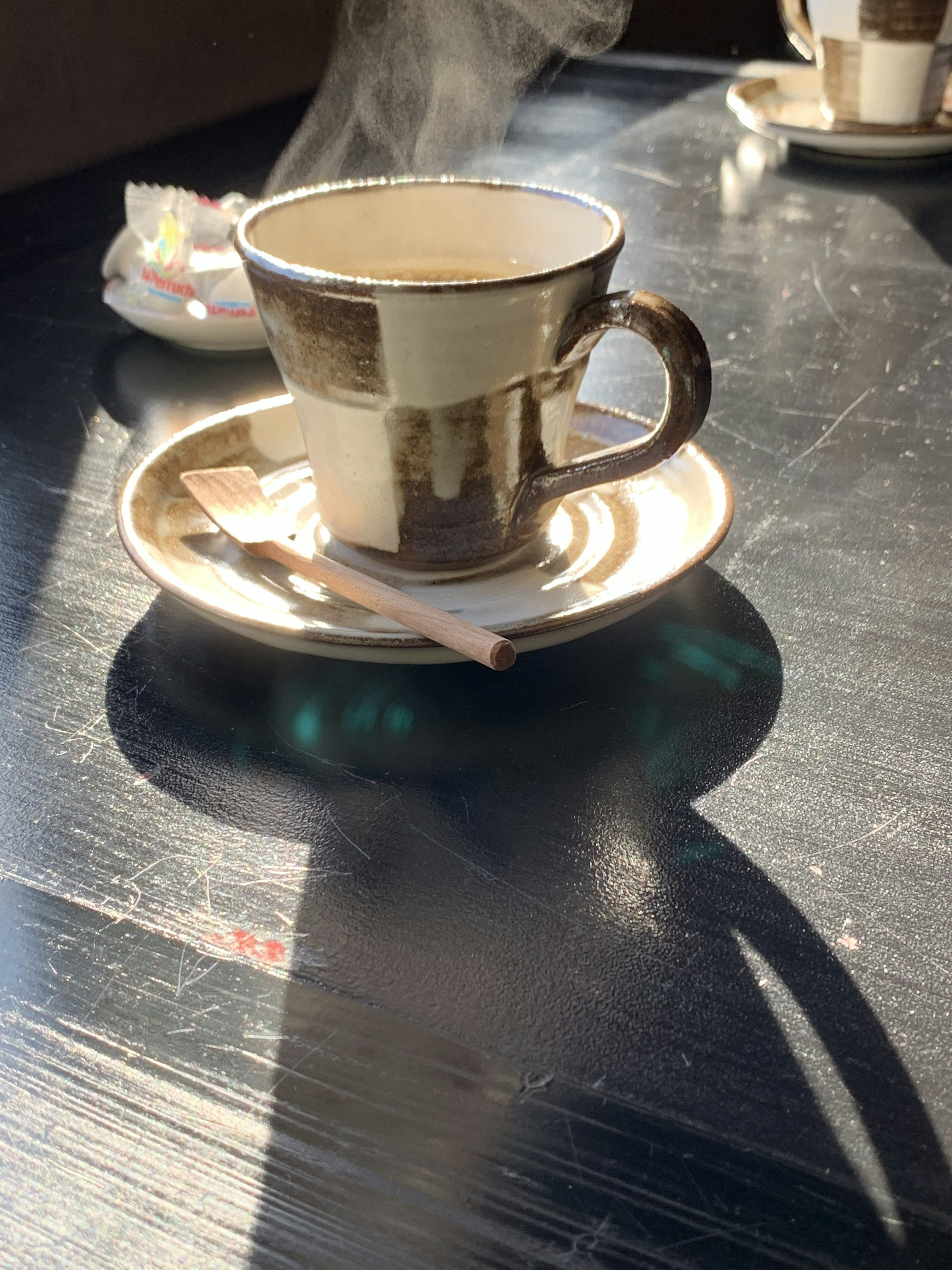 Taza de cerámica con bebida caliente en un platillo sobre una mesa