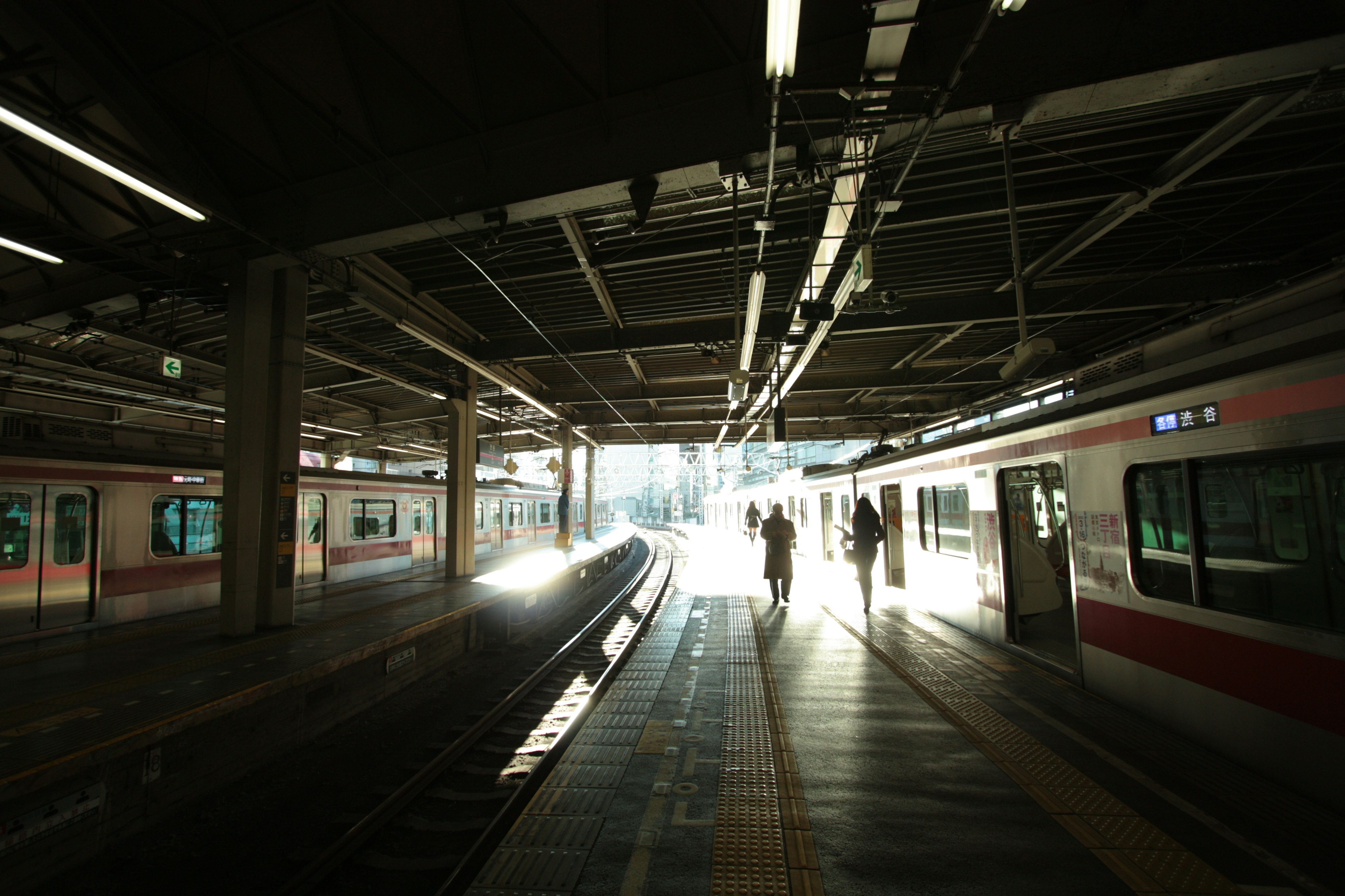 Una scena in una stazione ferroviaria al tramonto con persone che camminano sulla banchina