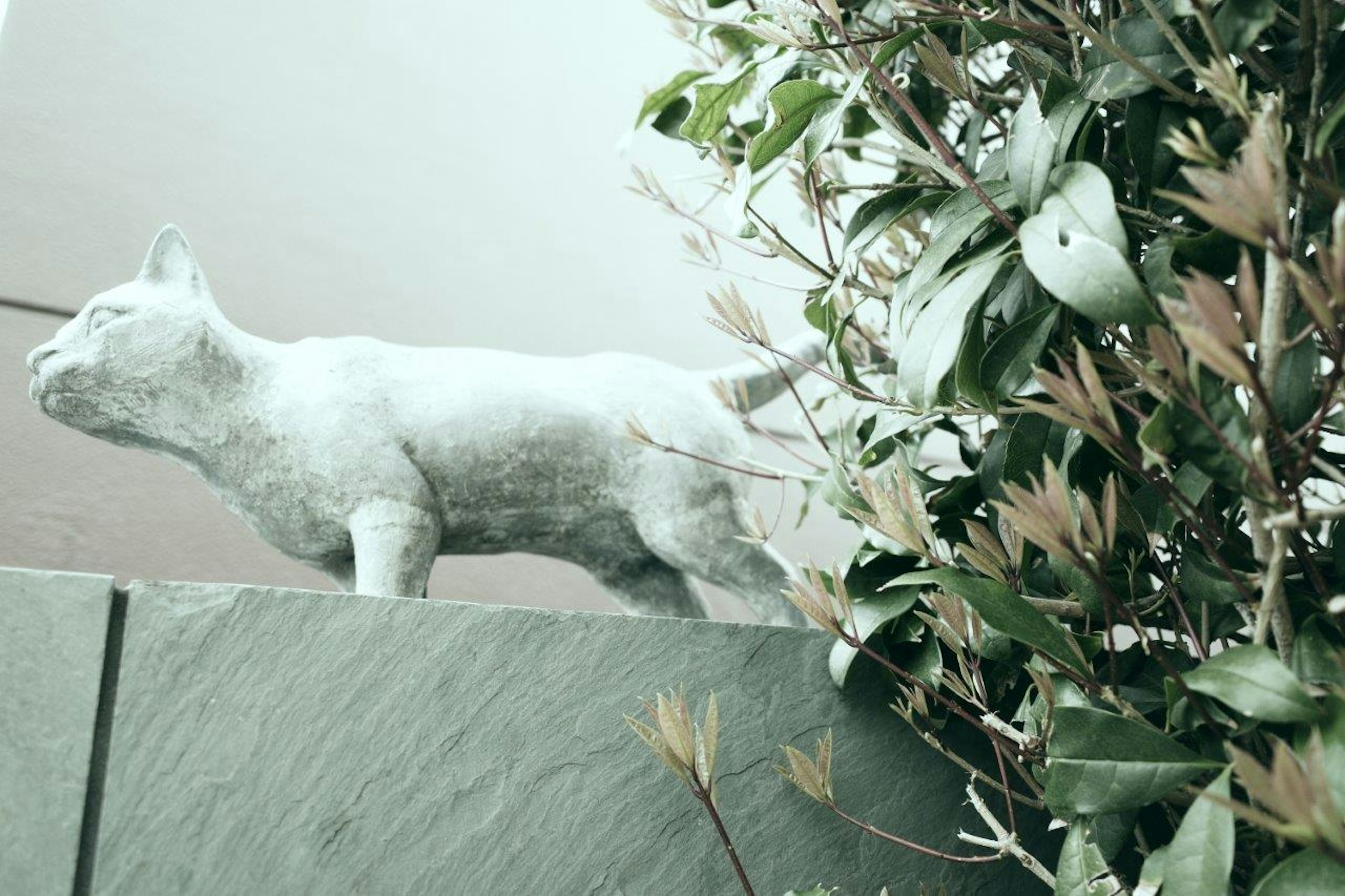 Una escultura de gato blanco caminando sobre un seto