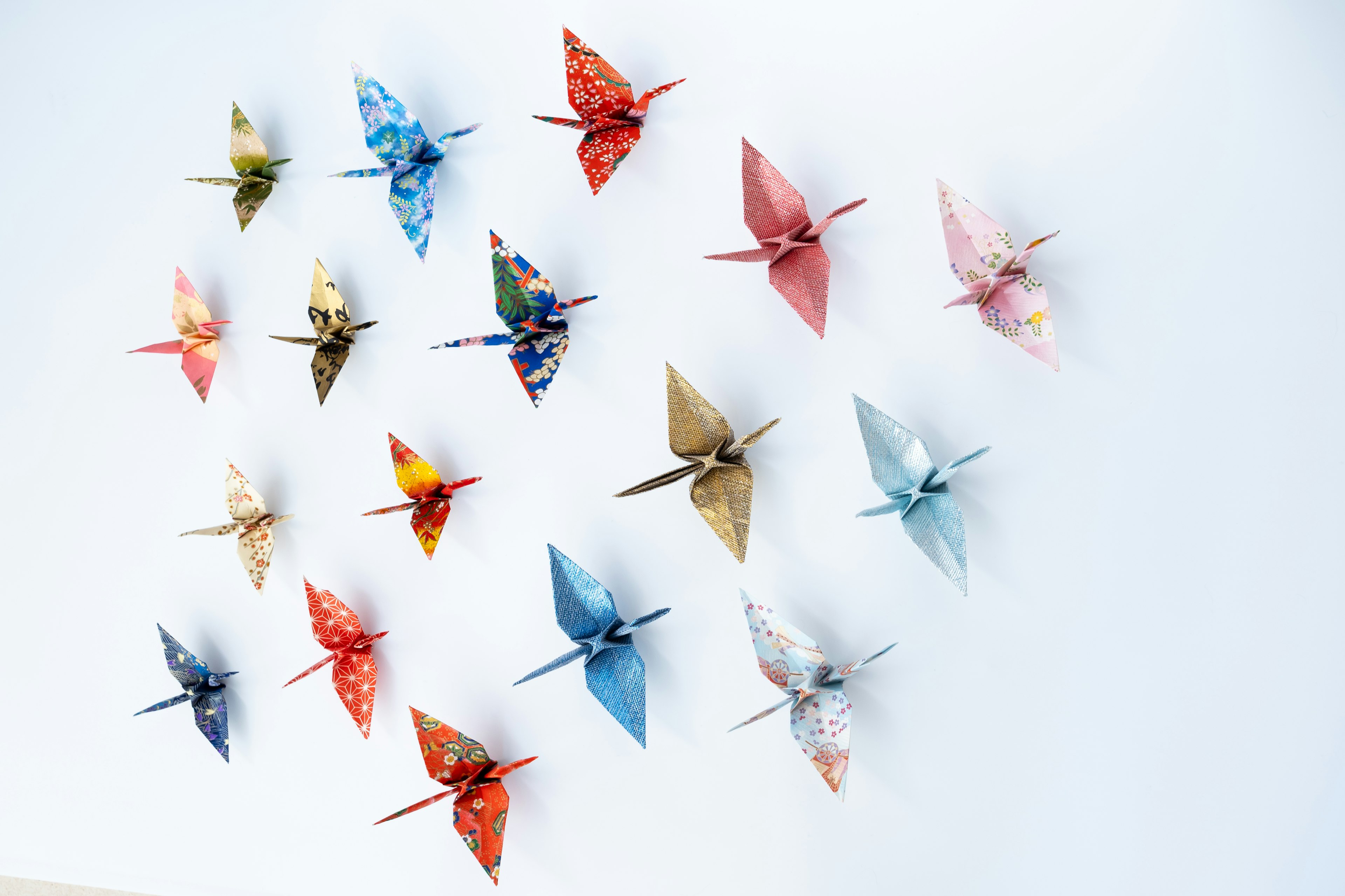 Colorful origami cranes displayed on a white wall