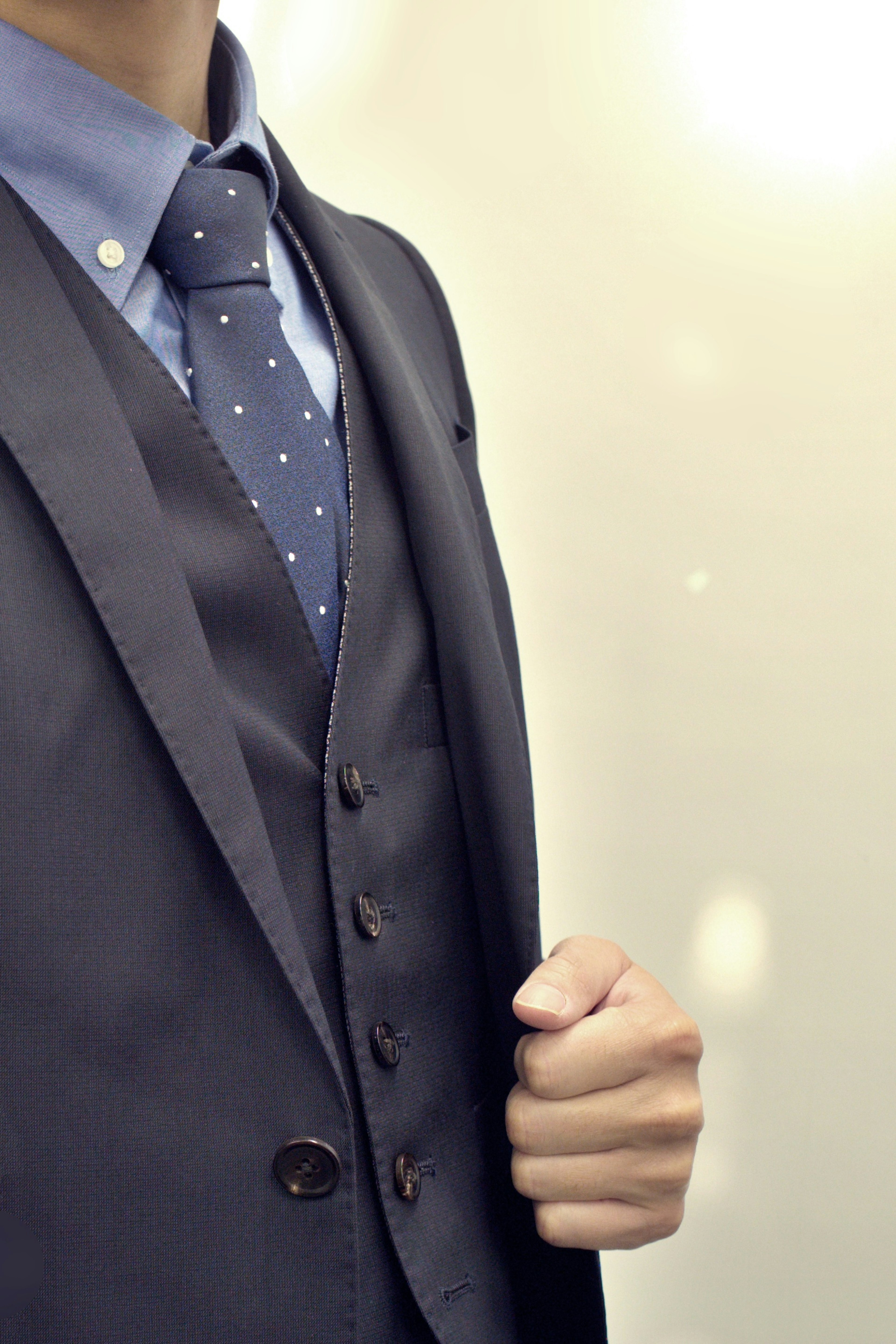 Close-up of a man in a suit with a fitted vest and polka dot tie