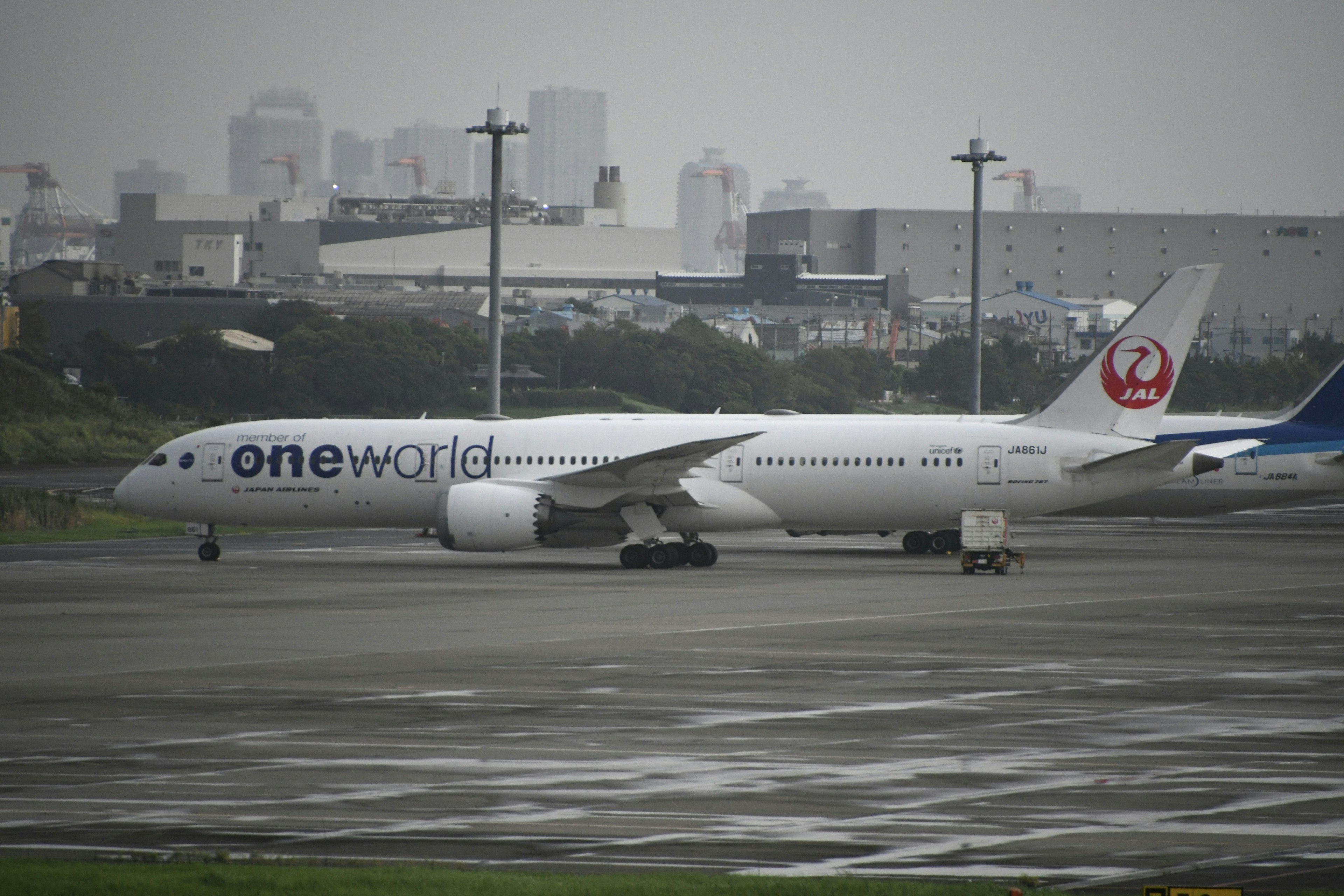 Boeing 777 de Japan Airlines en la pista de un aeropuerto en un día lluvioso