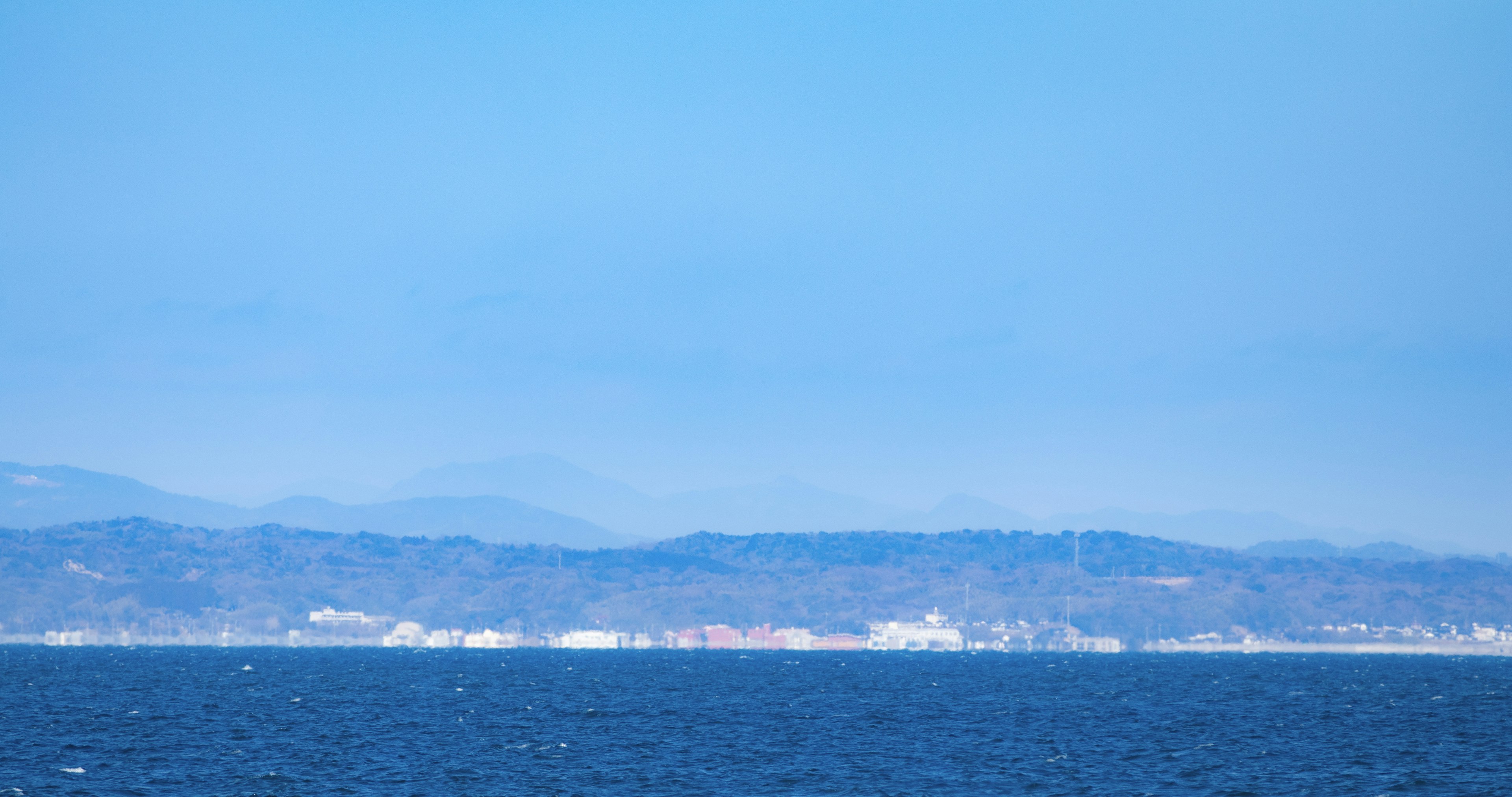 Pemandangan laut biru dan pegunungan jauh