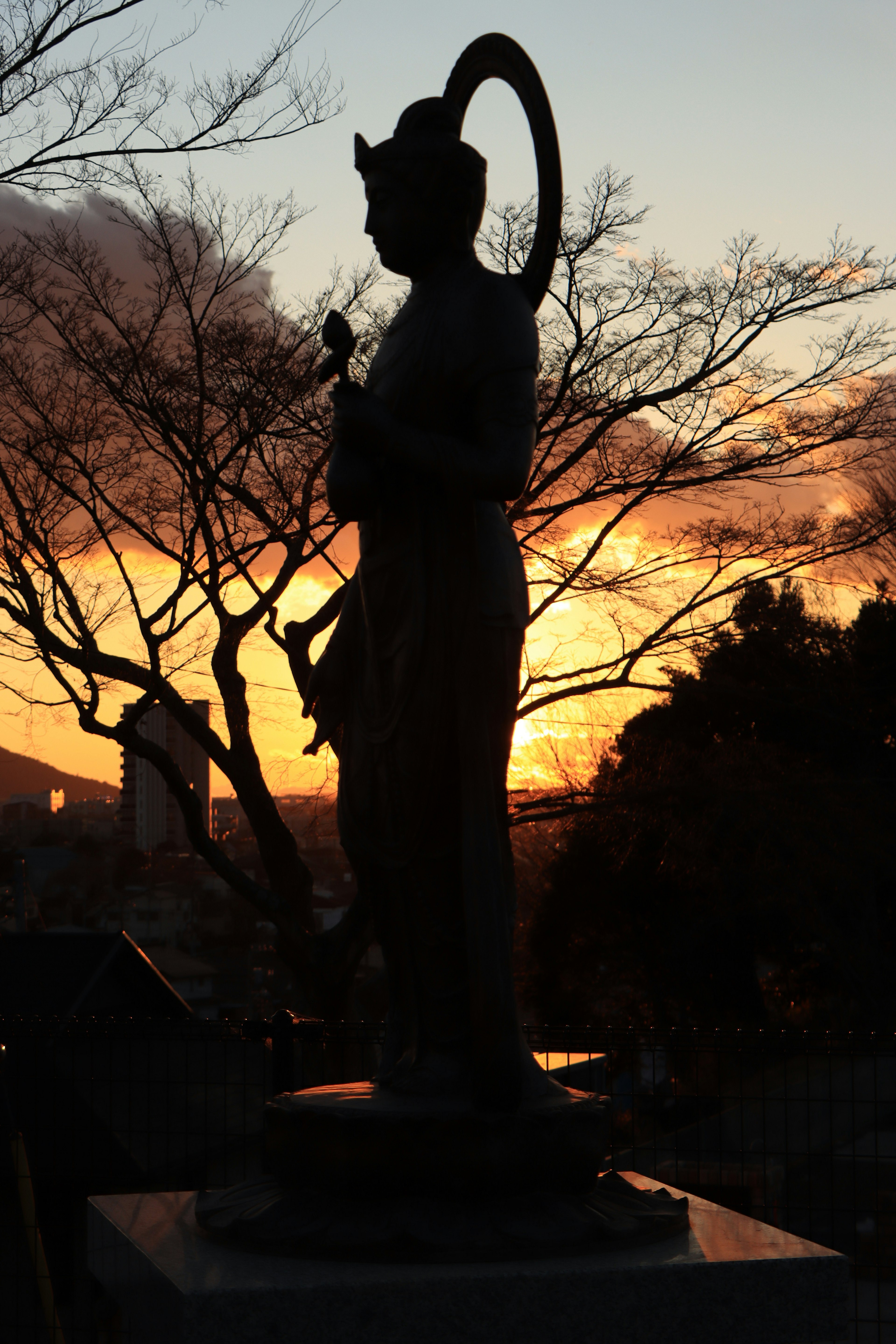 Silhouette of a statue against a sunset background