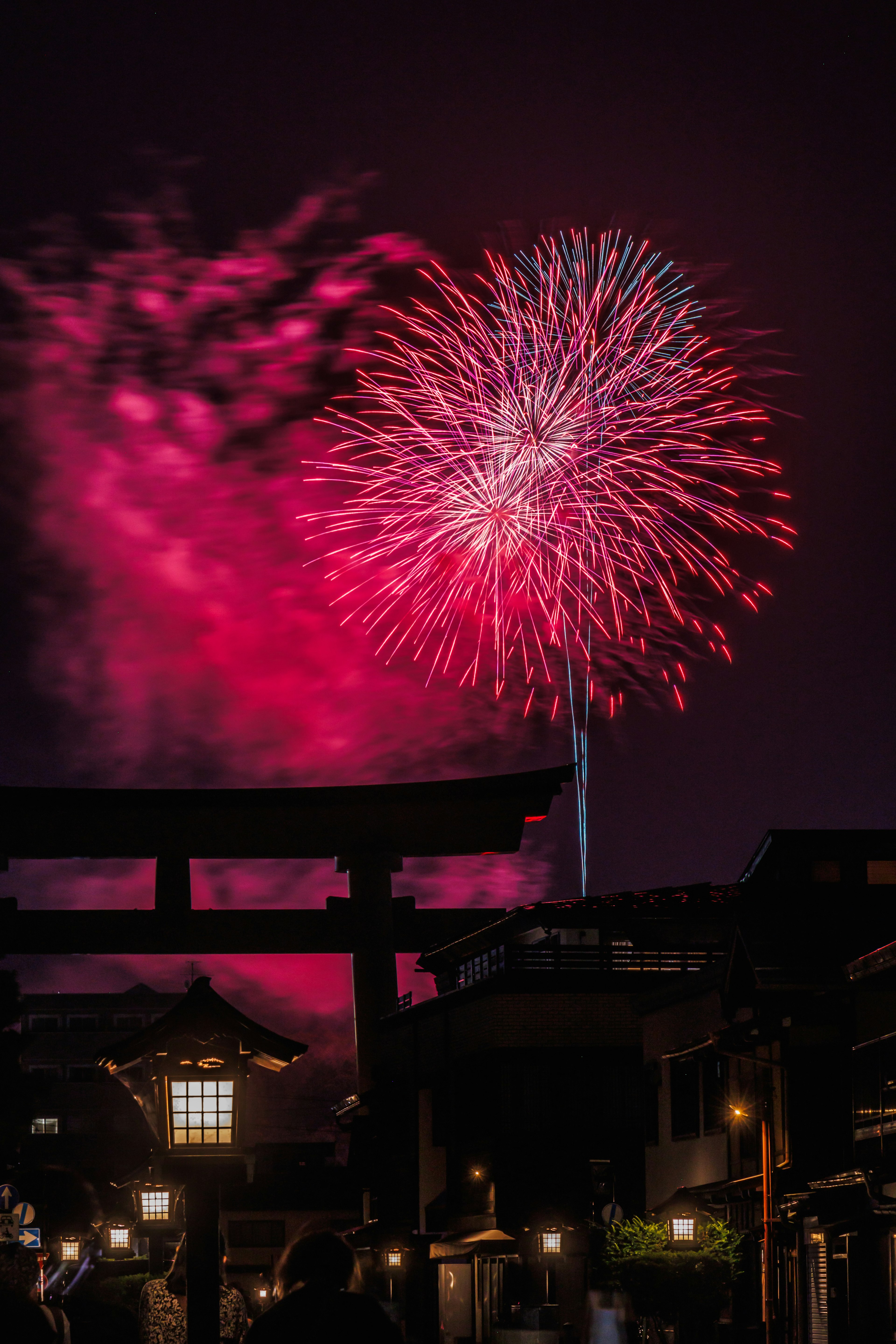 Feux d'artifice éclatant dans le ciel nocturne avec la silhouette d'un torii