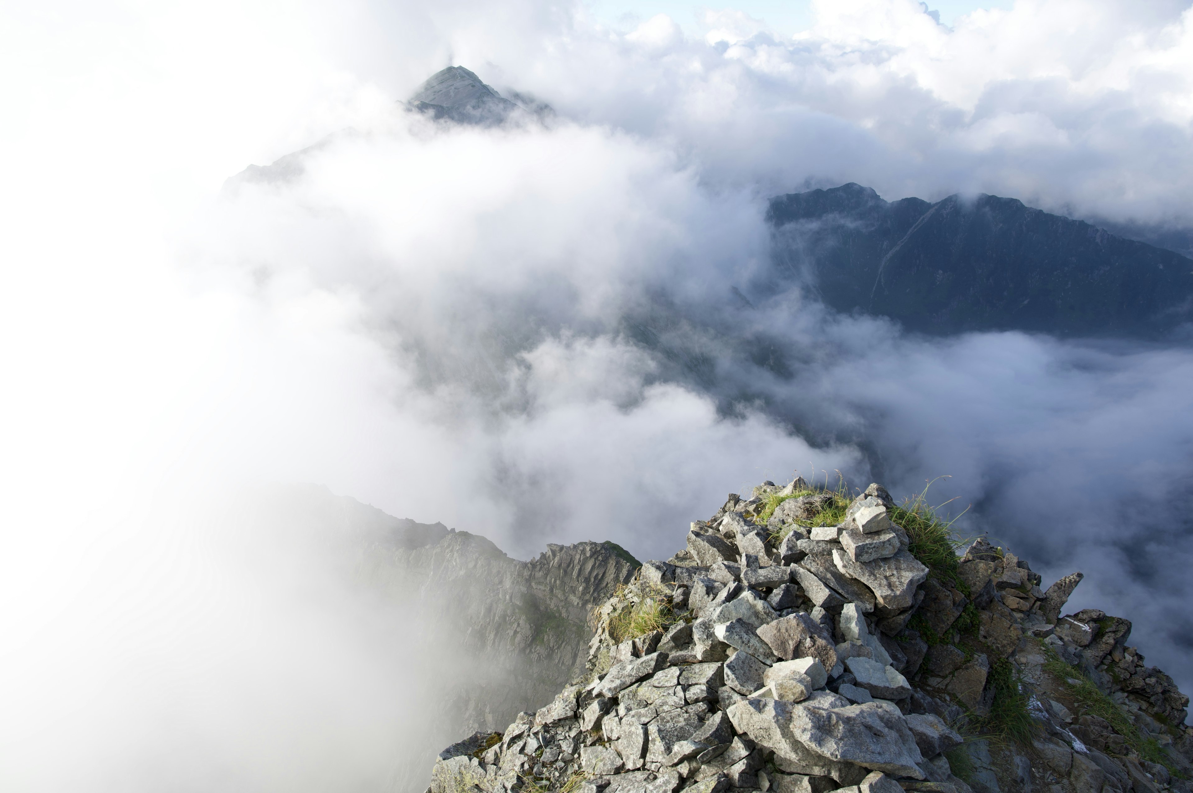 Vista desde un pico montañoso envuelto en niebla cumbre rocosa con nubes