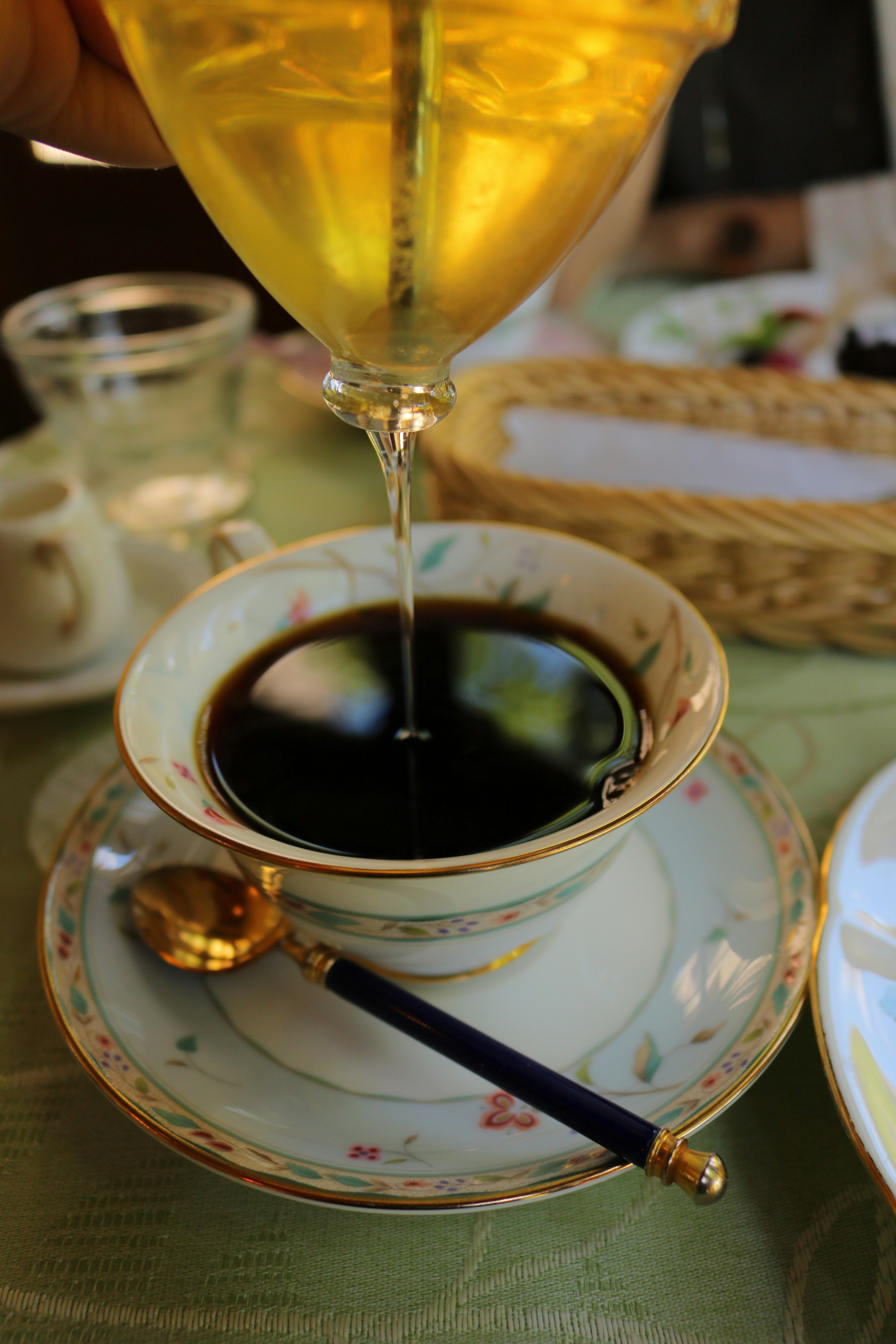 Café noir versé dans une tasse délicate de couleur crème avec une cuillère en or