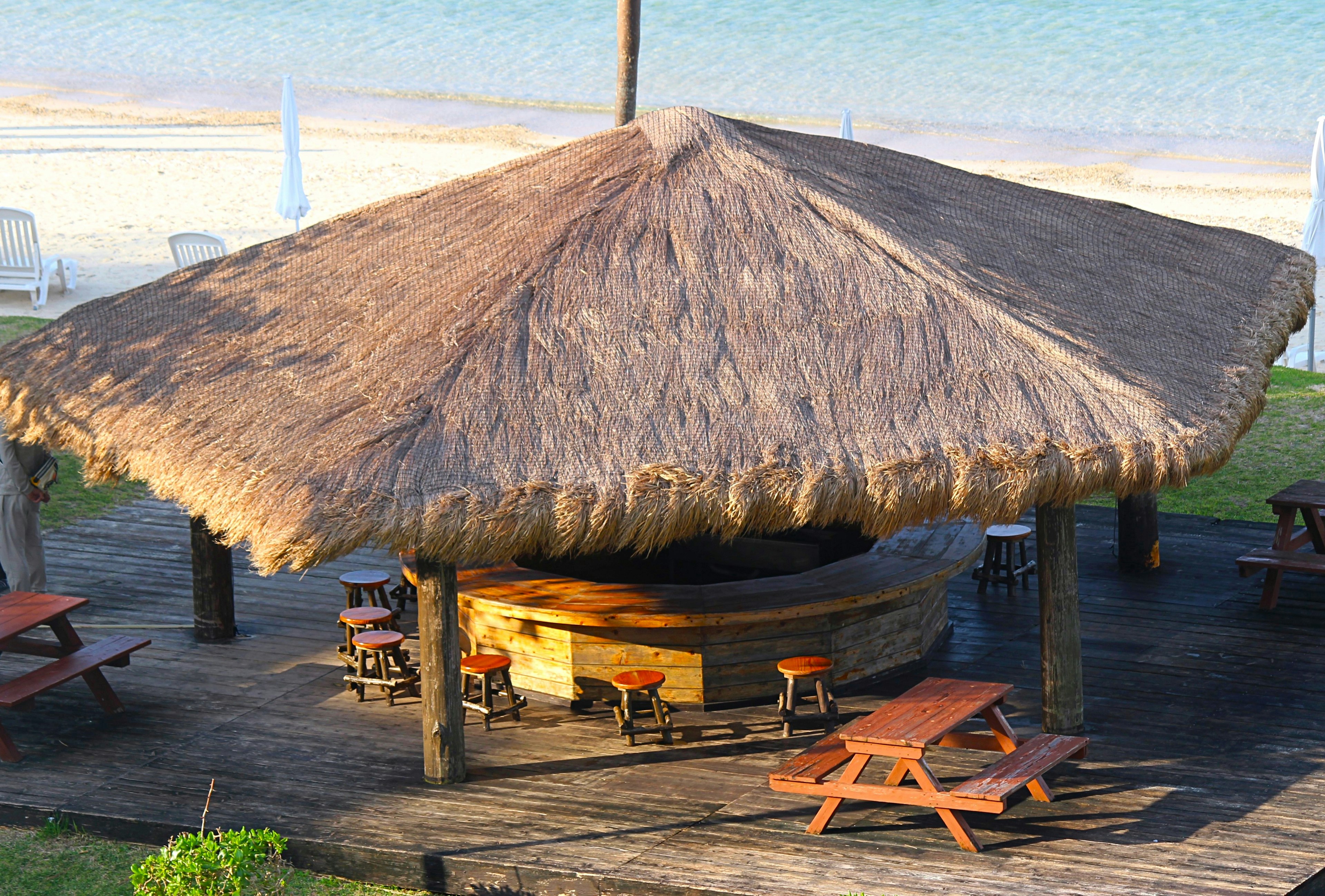 Thatched roof pavilion near the beach with wooden tables