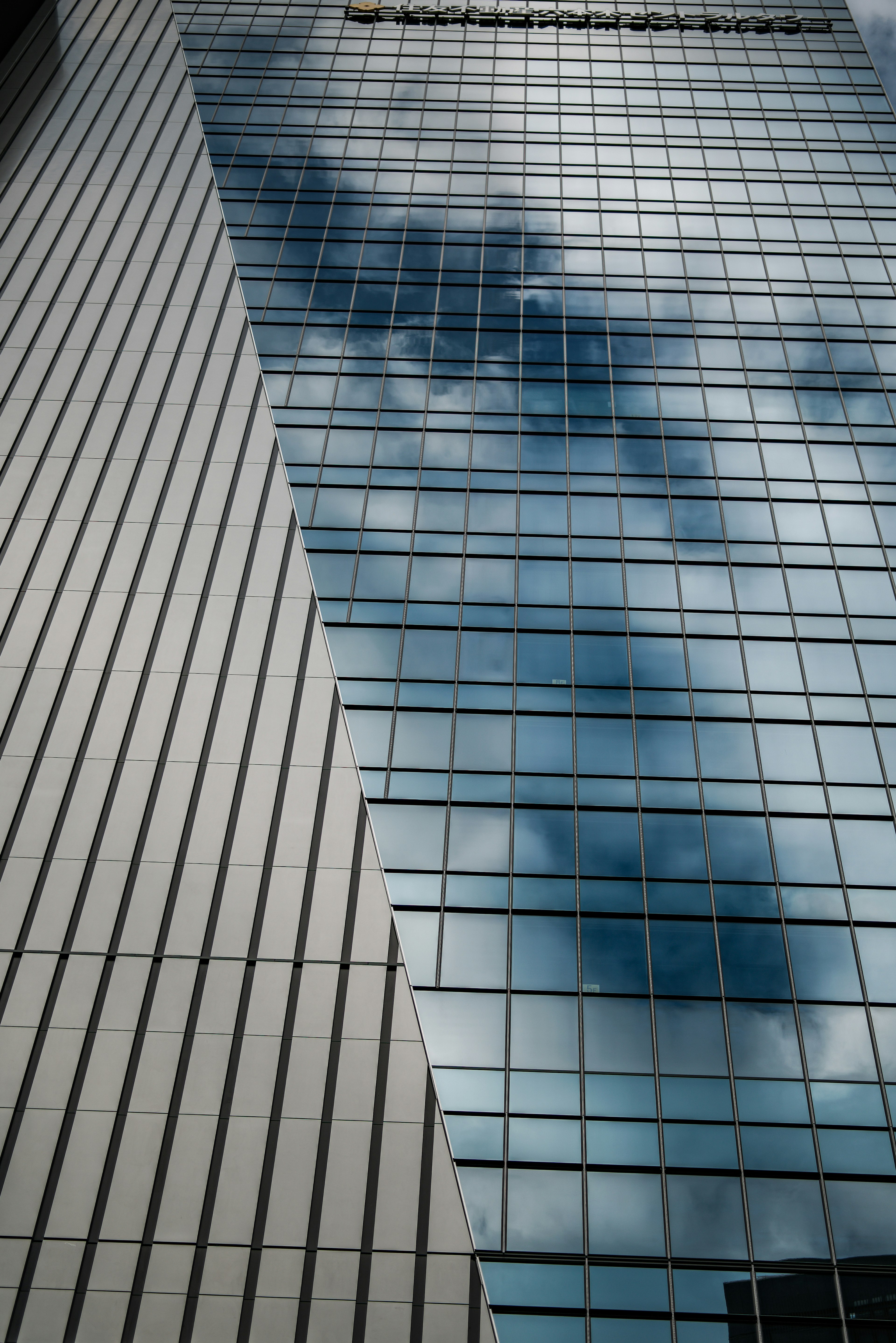 Diagonal glass building with reflections and striped facade