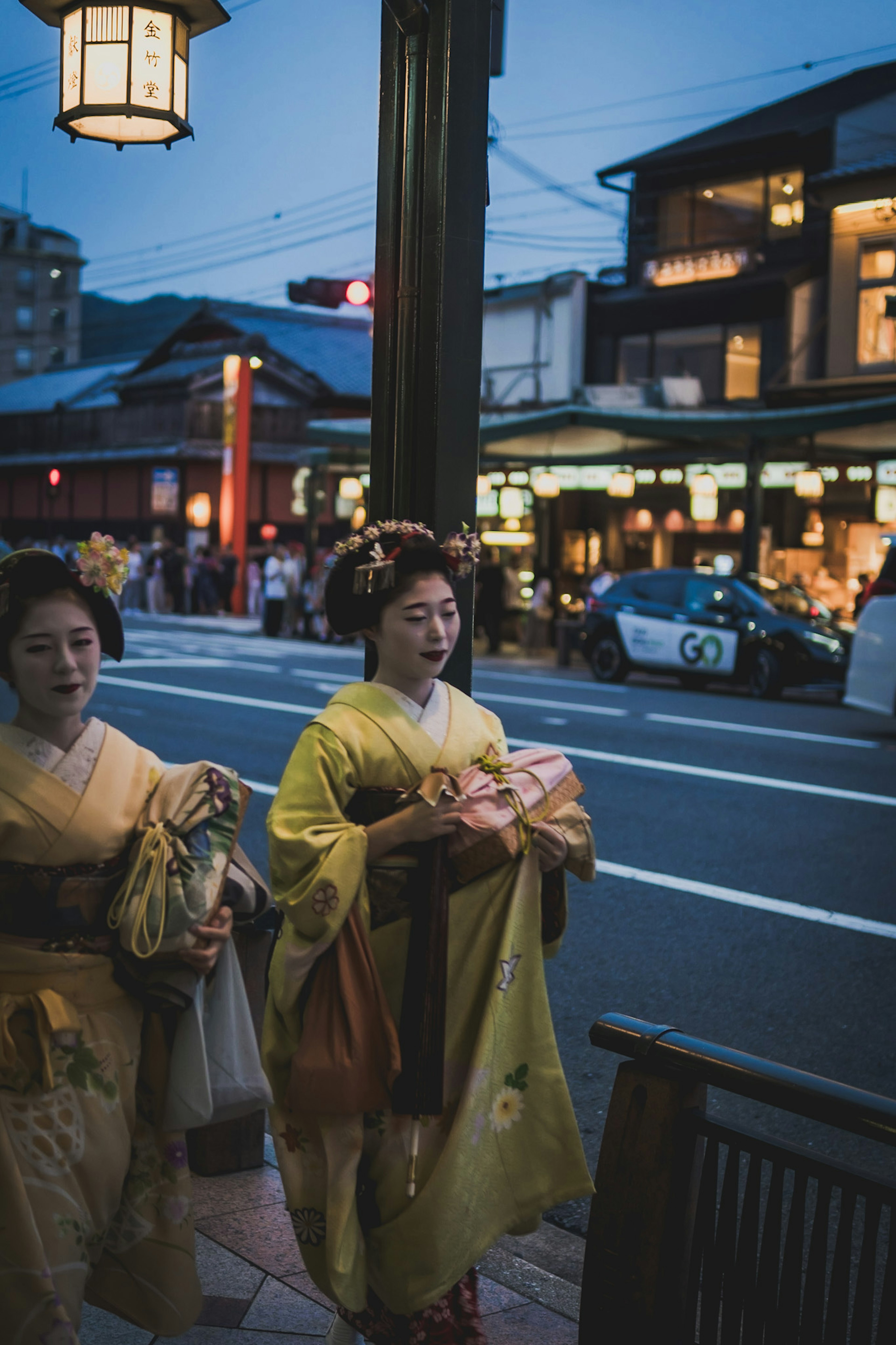 Wanita berpakaian kimono berjalan di jalan malam dengan arsitektur tradisional