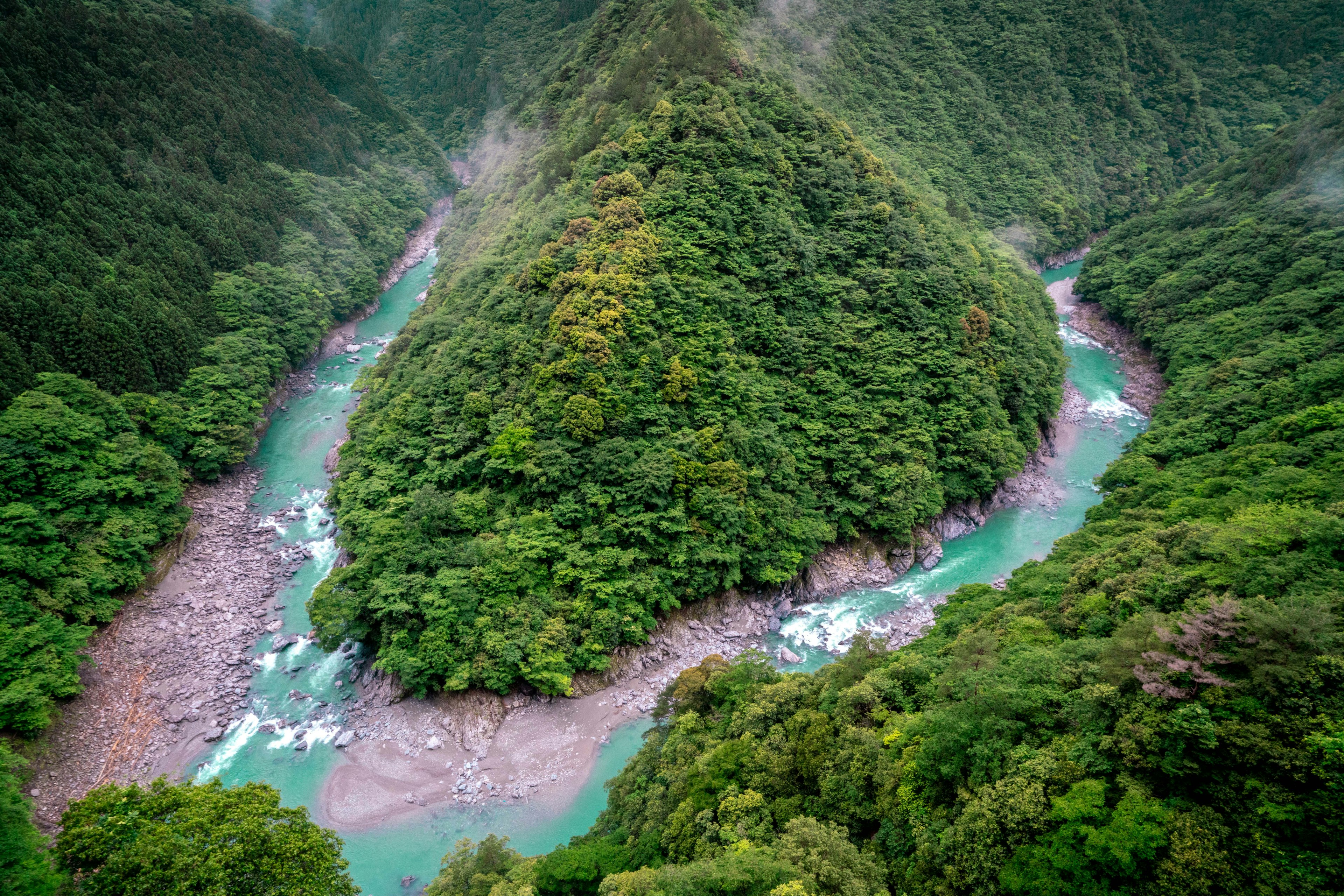 Vue aérienne d'une rivière sinueuse entourée de montagnes verdoyantes