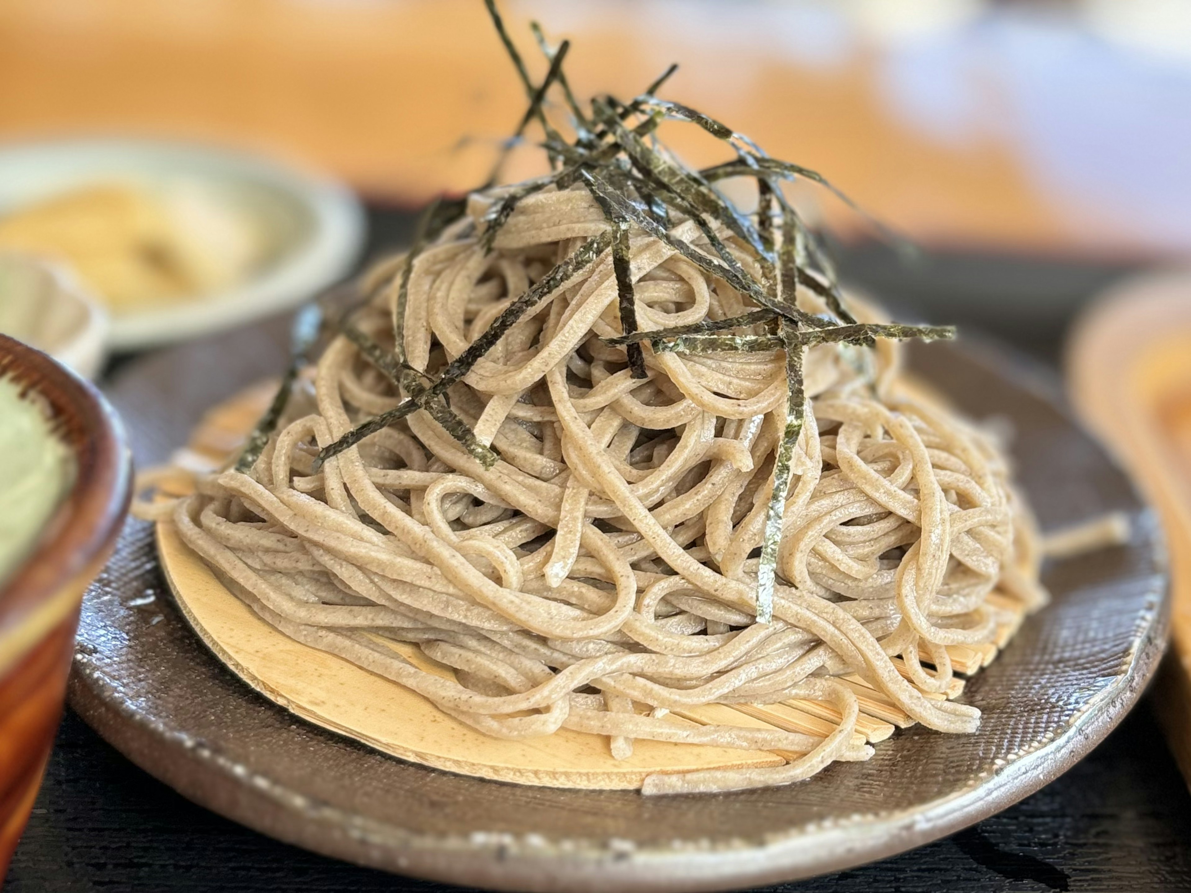 Un plat de nouilles soba joliment disposées sur une assiette avec des algues