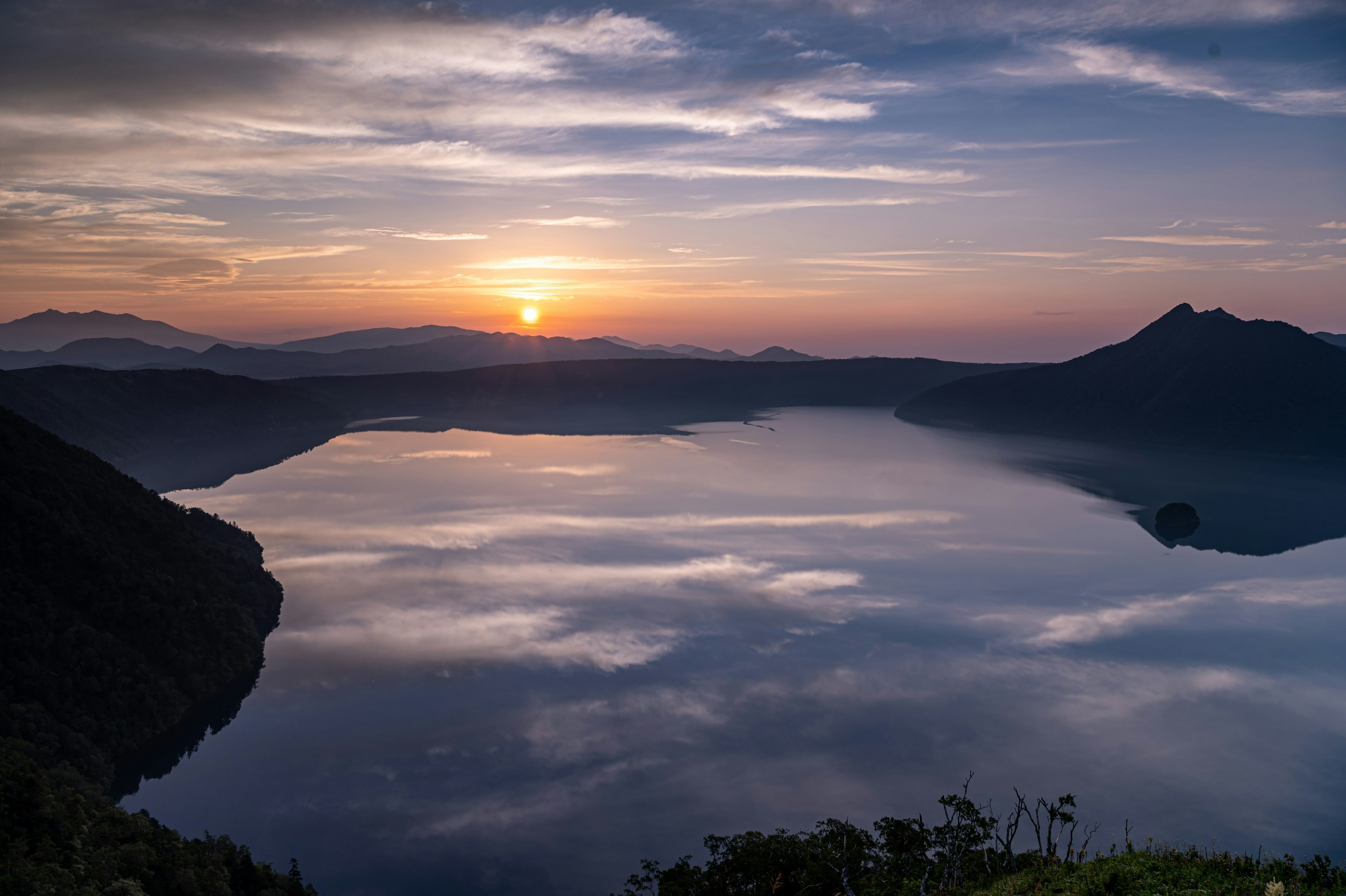 湖と山々を背景にした美しい夕日が映る風景