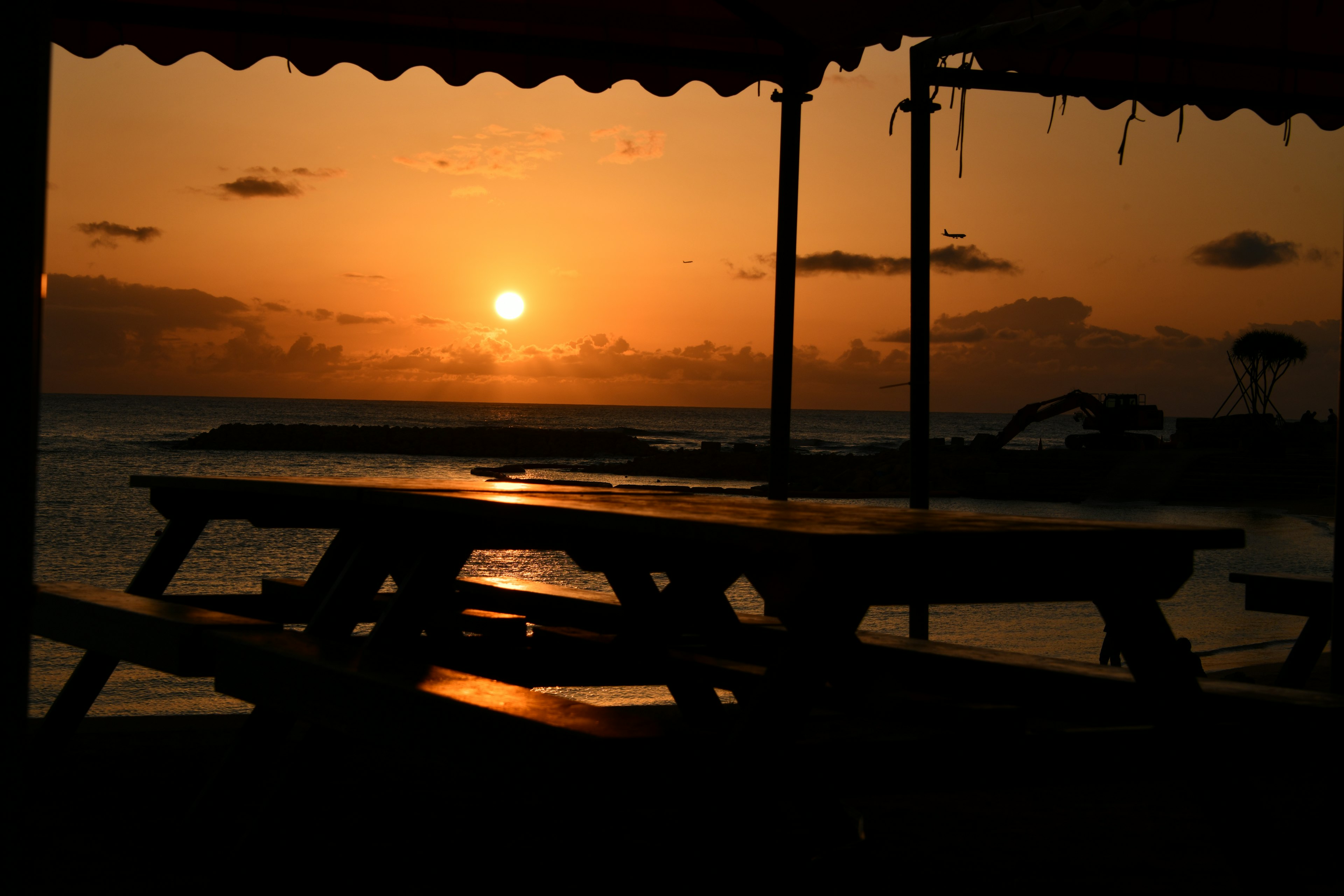 Silueta de una mesa y sillas junto al mar al atardecer