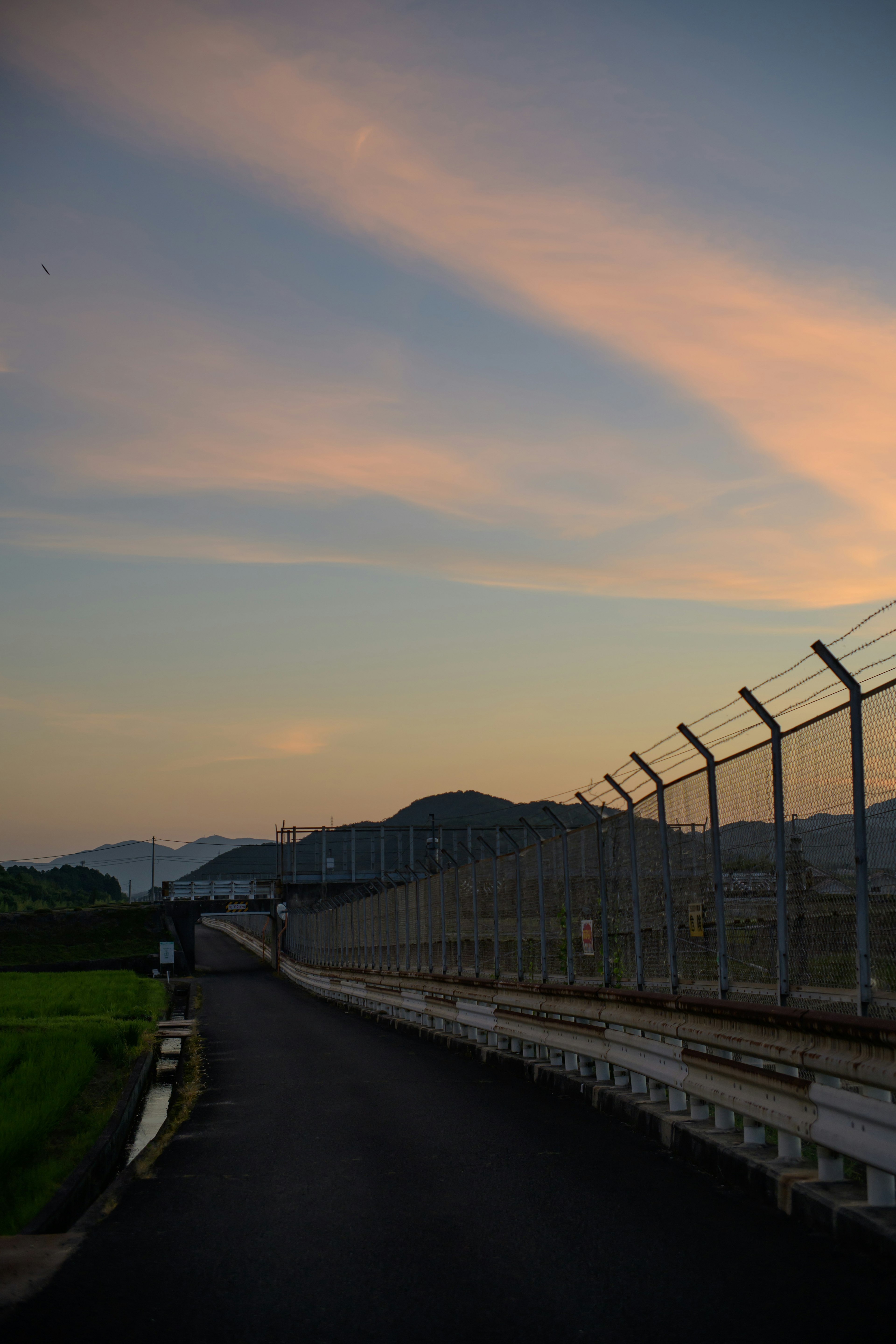 夕暮れの空とフェンスがある道路の風景