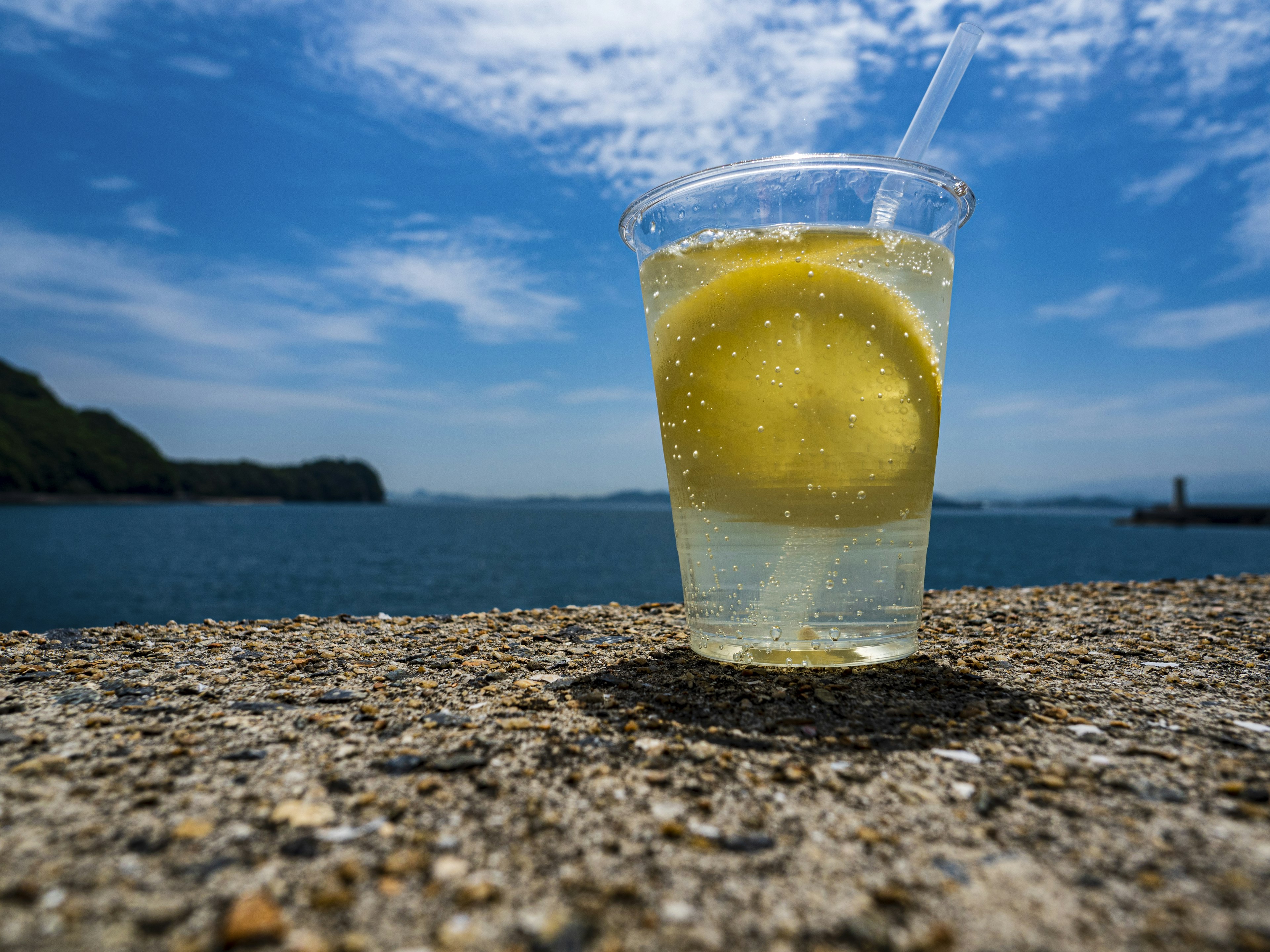 Minuman segar dengan lemon di latar belakang laut dan langit biru