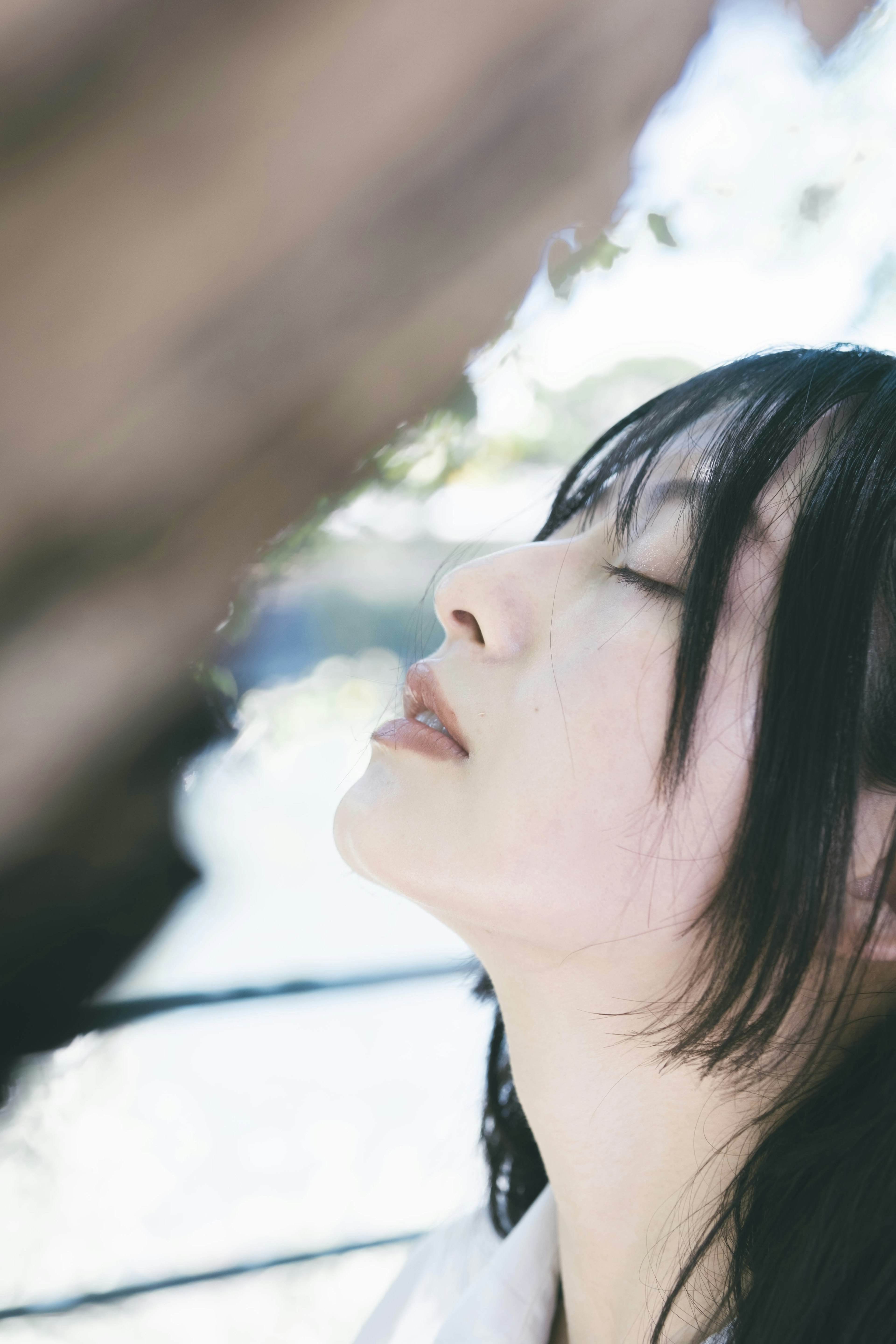 A woman with closed eyes displaying a serene expression captured in a natural setting