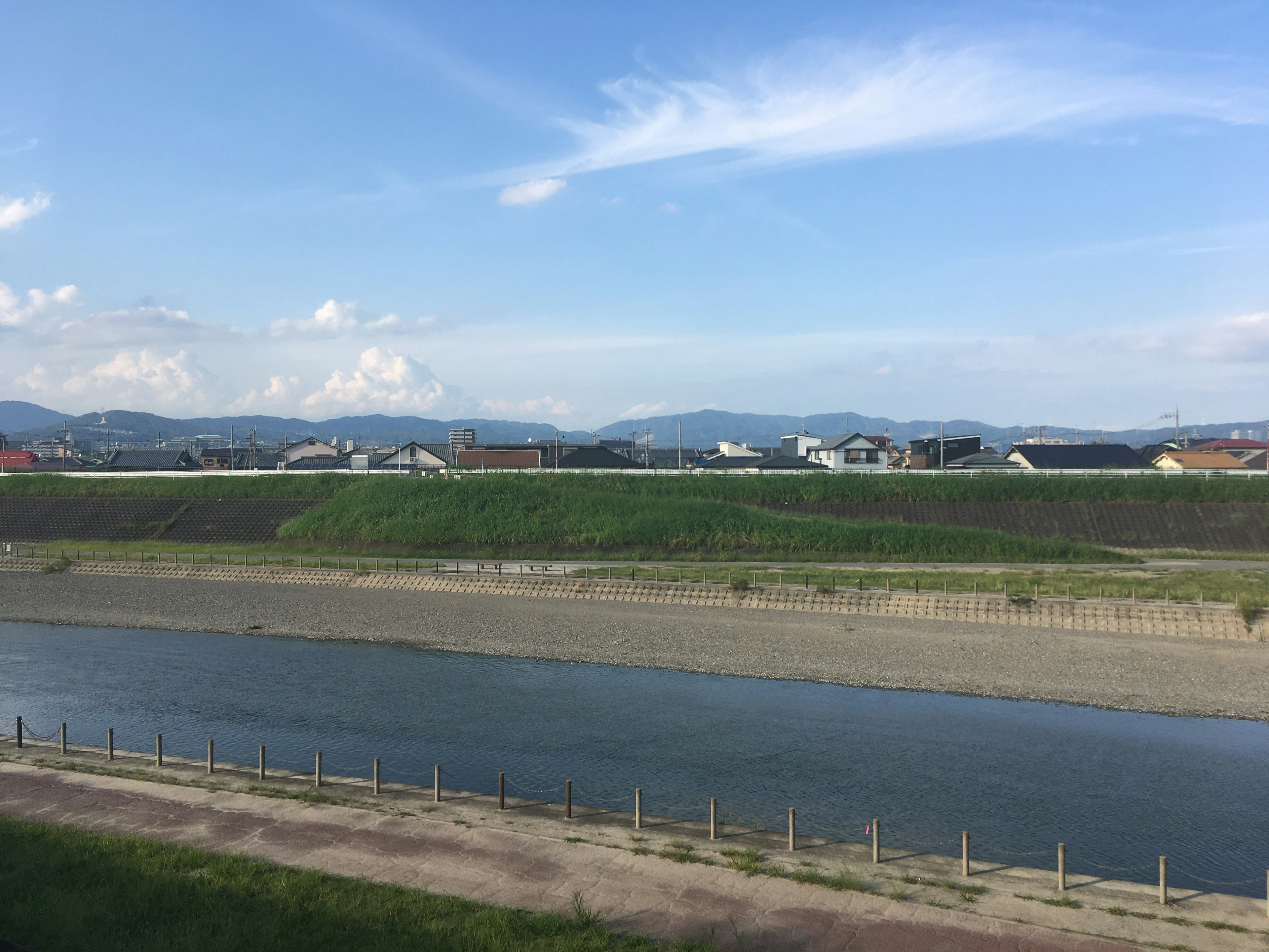 青い空と川が広がる風景 緑の草地と遠くの山々