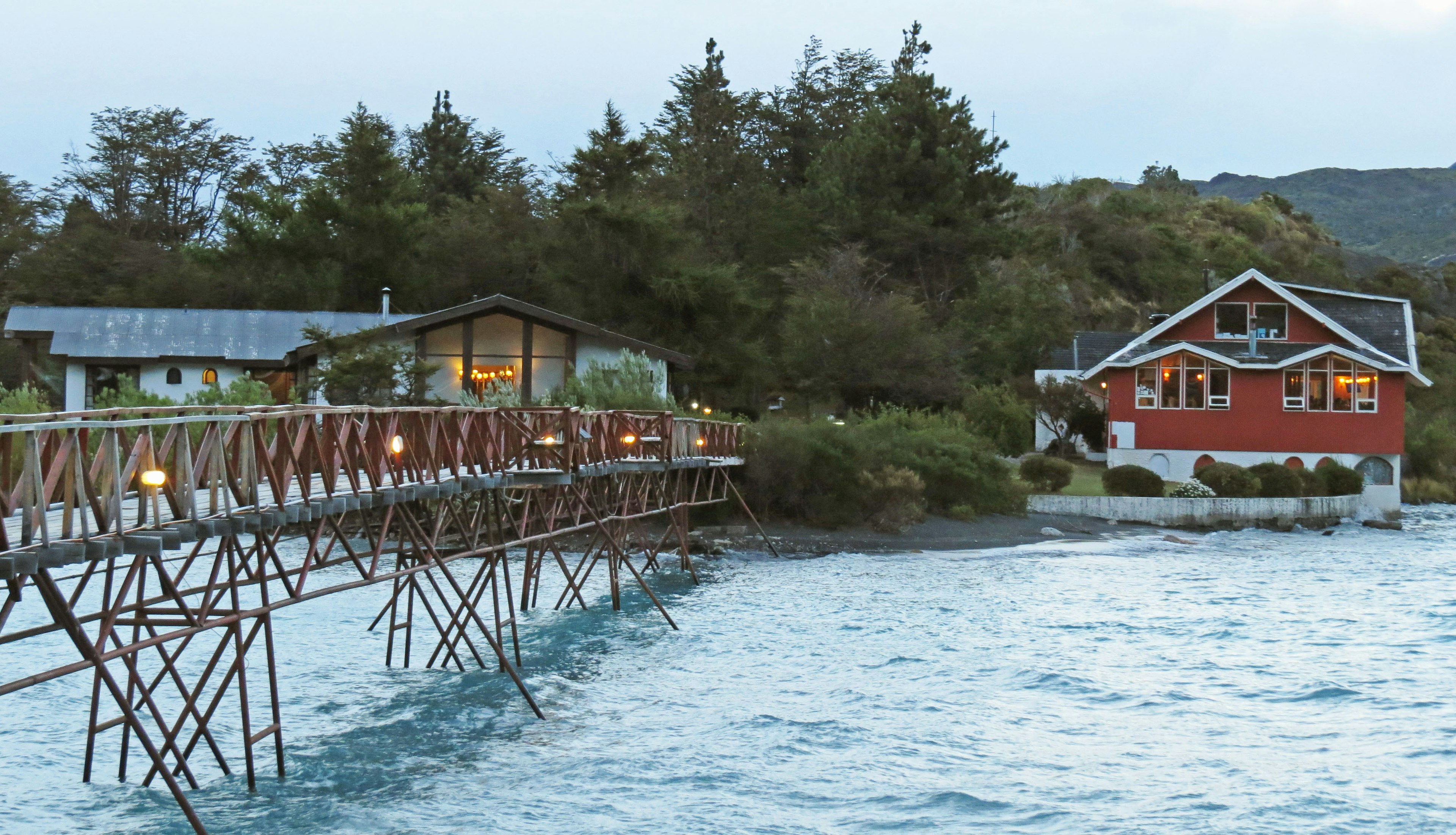 Scenic view of a wooden pier and a red house by the lake