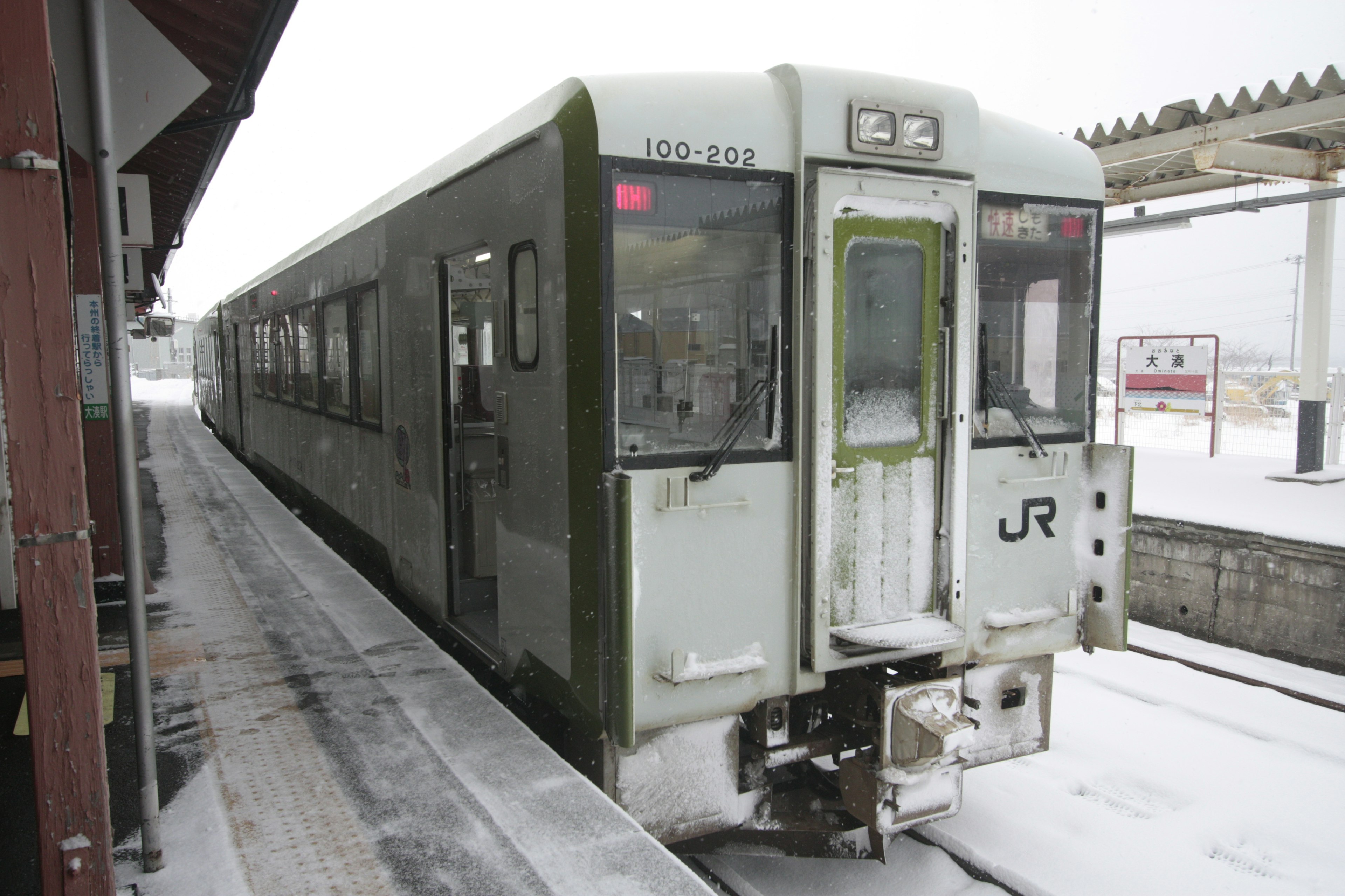 雪に覆われた駅に停車中の緑色の列車