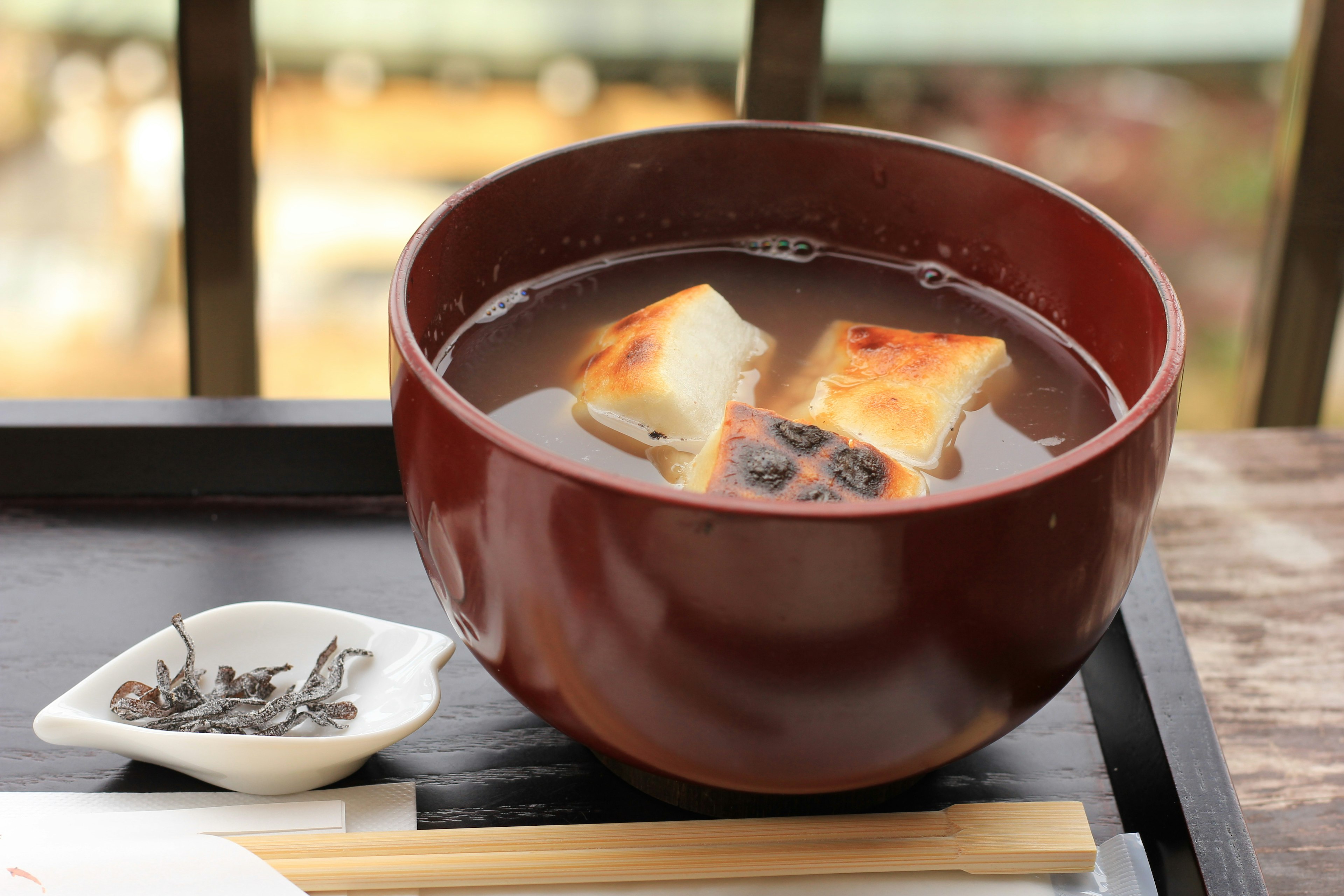 Rote Schüssel mit Mochi und schwarzen Bohnen Suppe