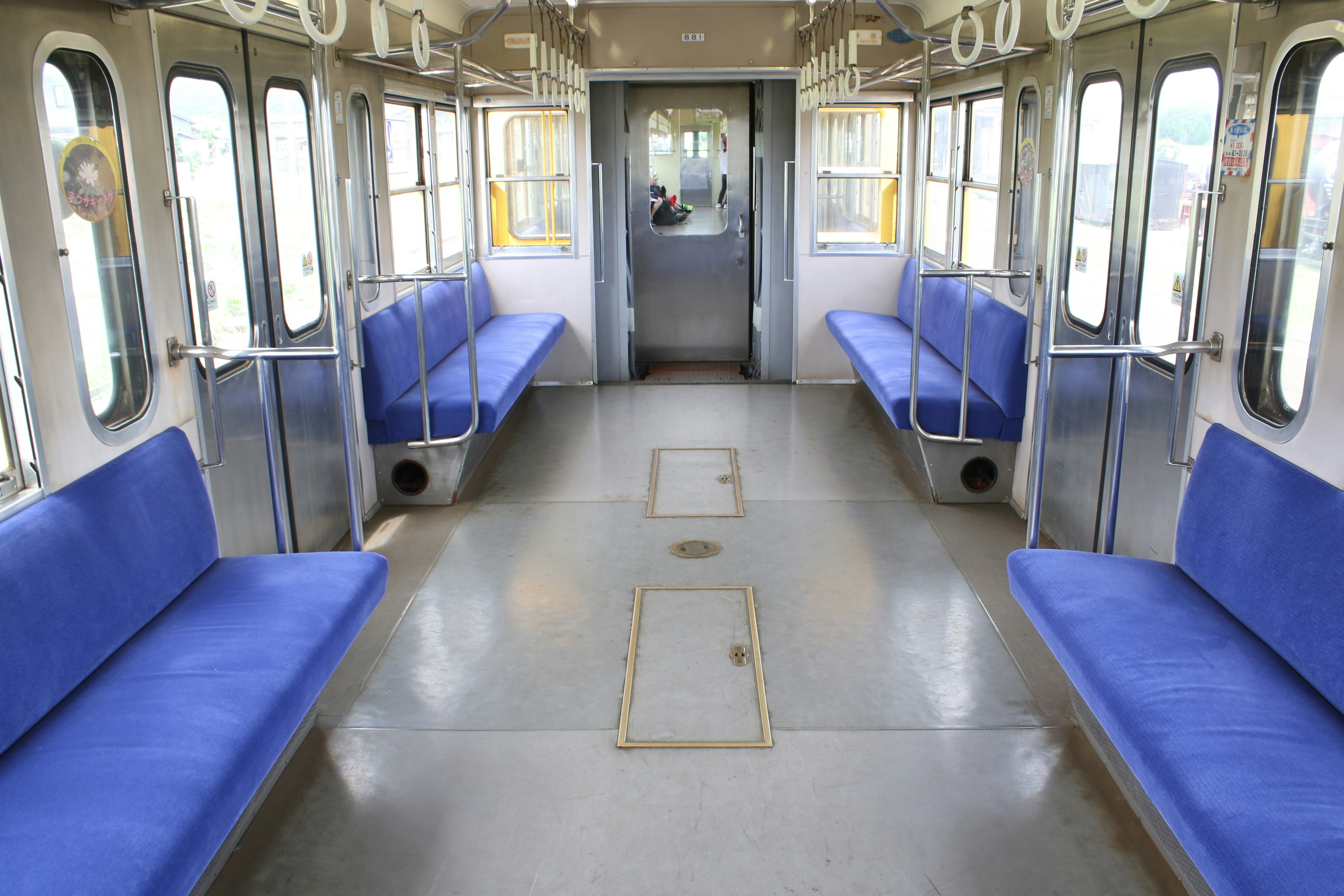 Interior of an empty train carriage with blue benches