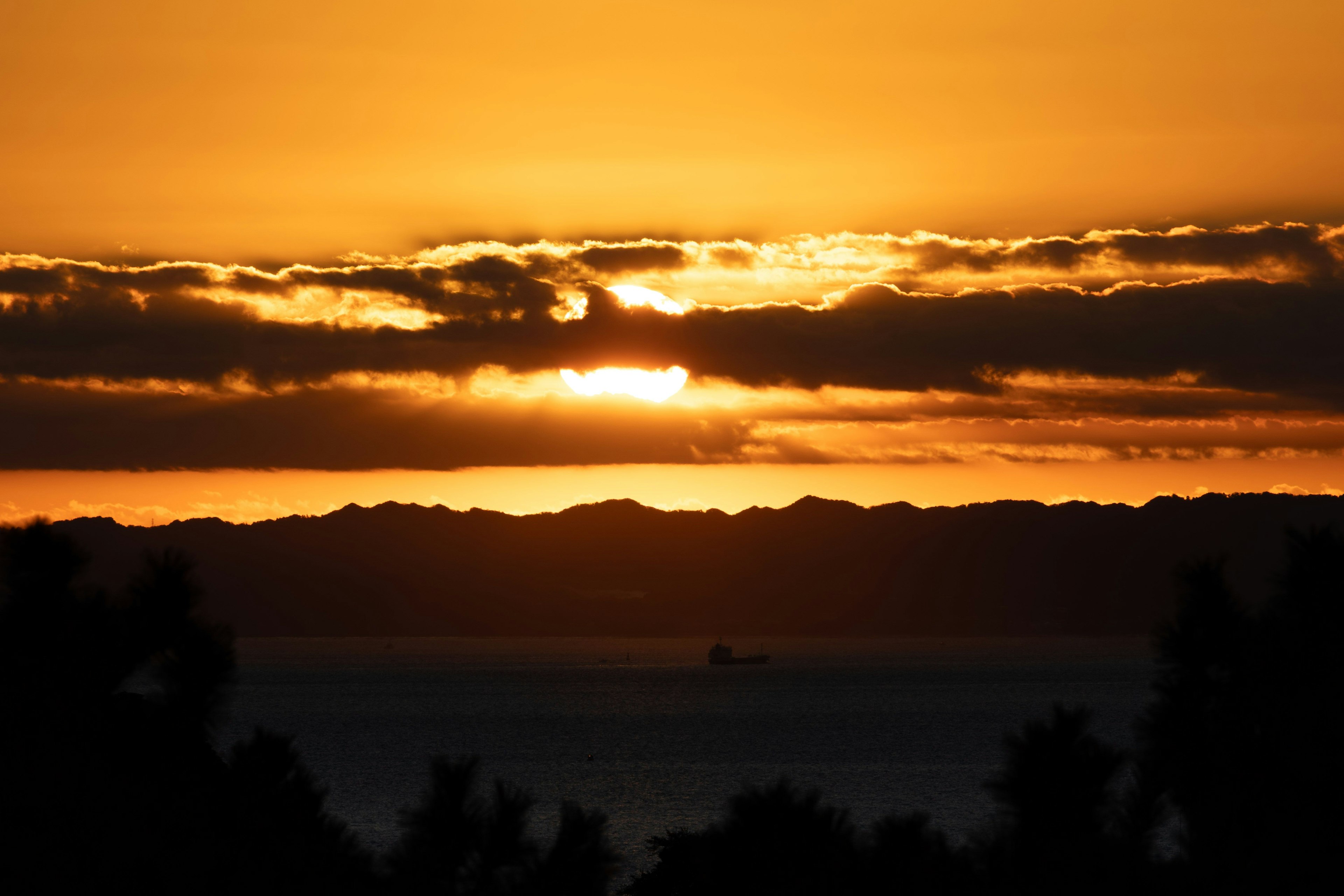 美しい夕日が海の上に沈む様子と雲のシルエット