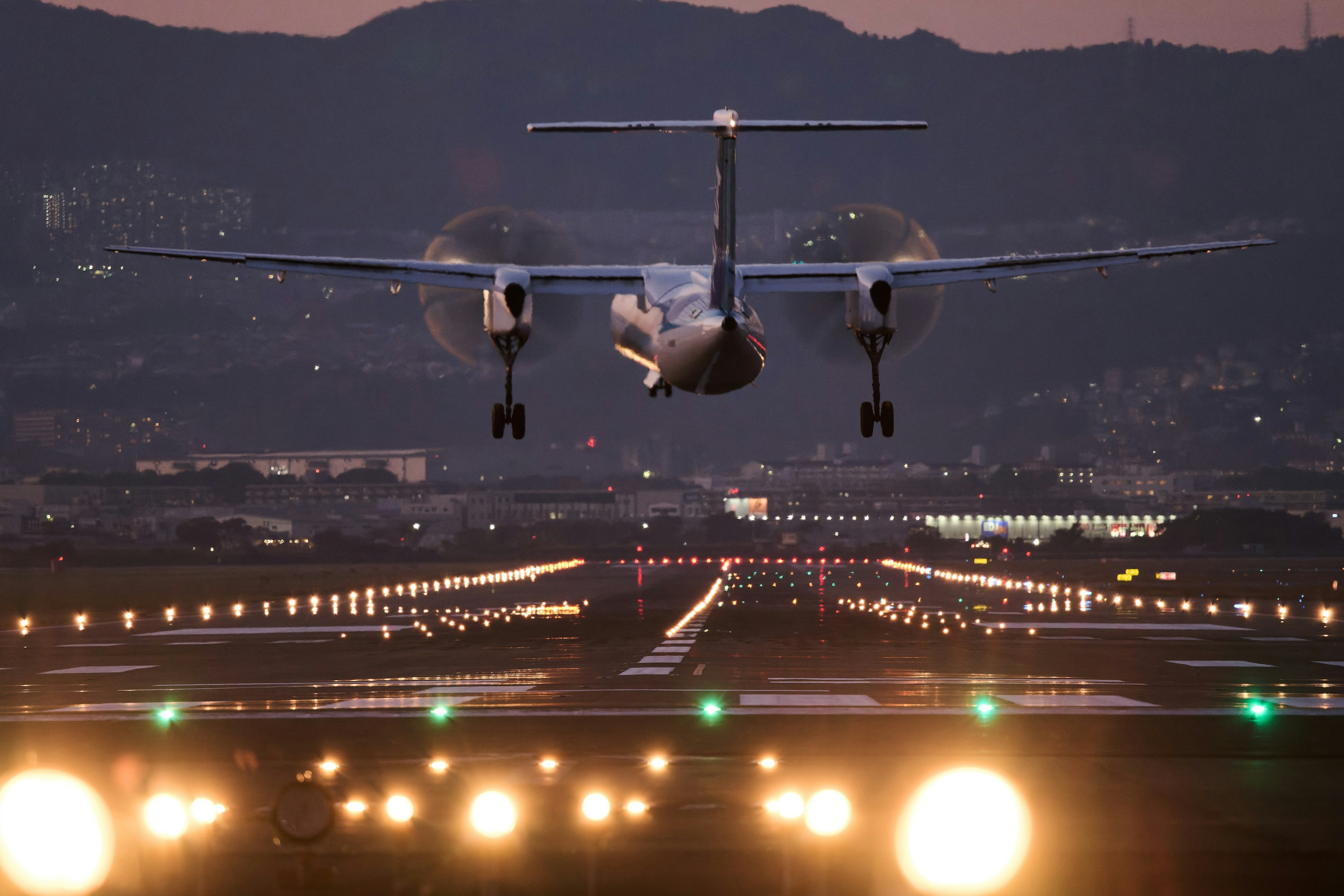 Aereo in atterraggio sulla pista al crepuscolo con luci illuminate